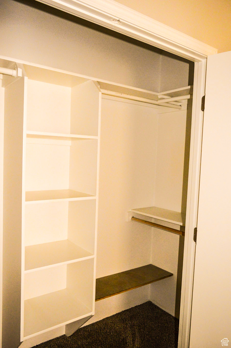 View of master bedroom closet with built in shelving in middle and each end.