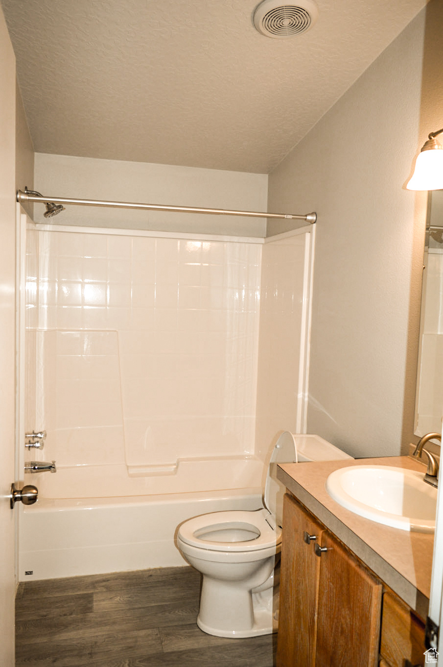 Full bathroom with vanity, toilet, hardwood / wood-style floors, and a textured ceiling