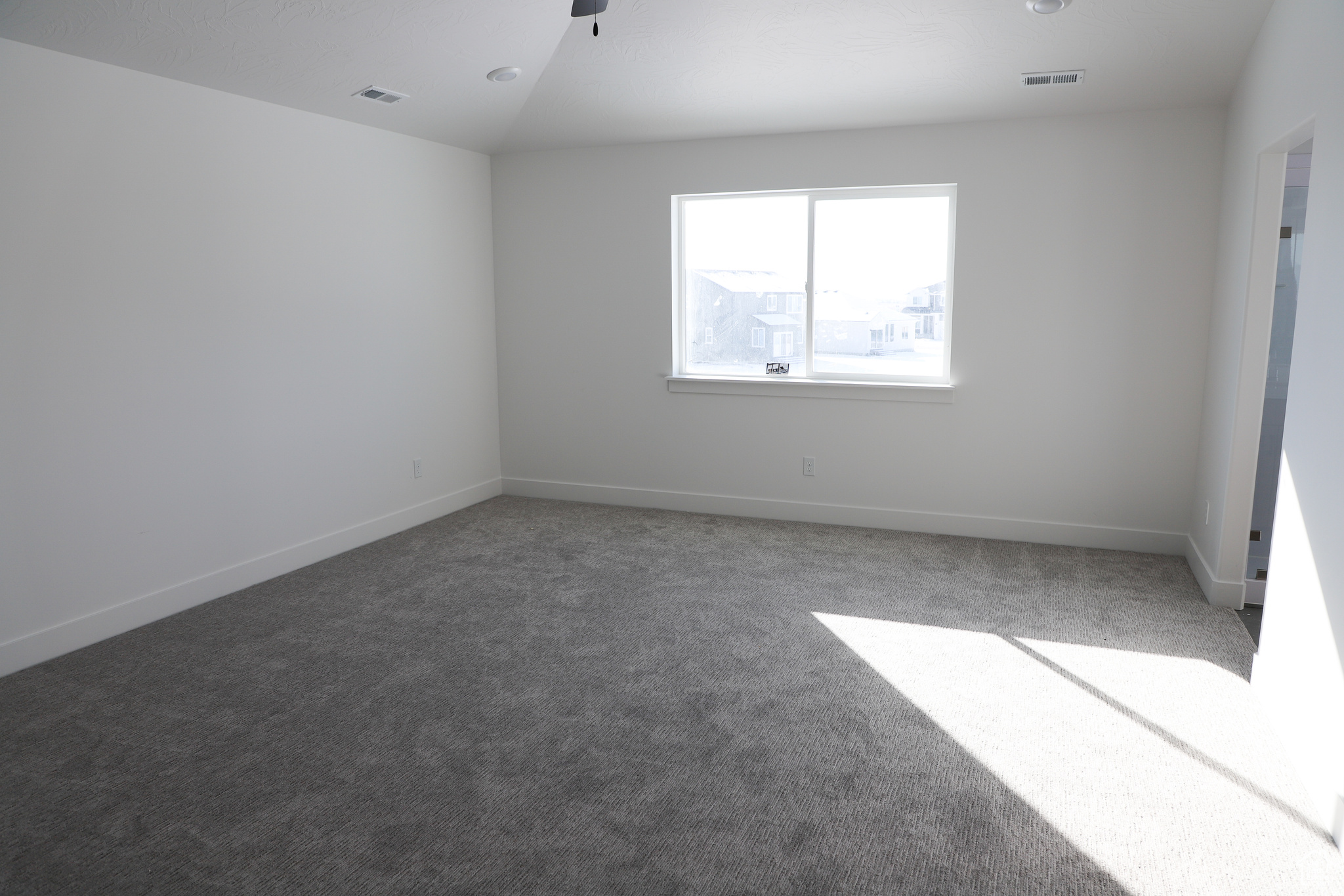 Carpeted empty room featuring vaulted ceiling and ceiling fan