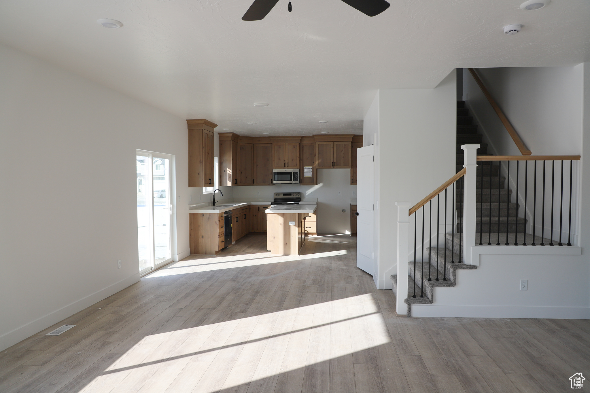 Kitchen with sink, stainless steel appliances, ceiling fan, and light wood-type flooring