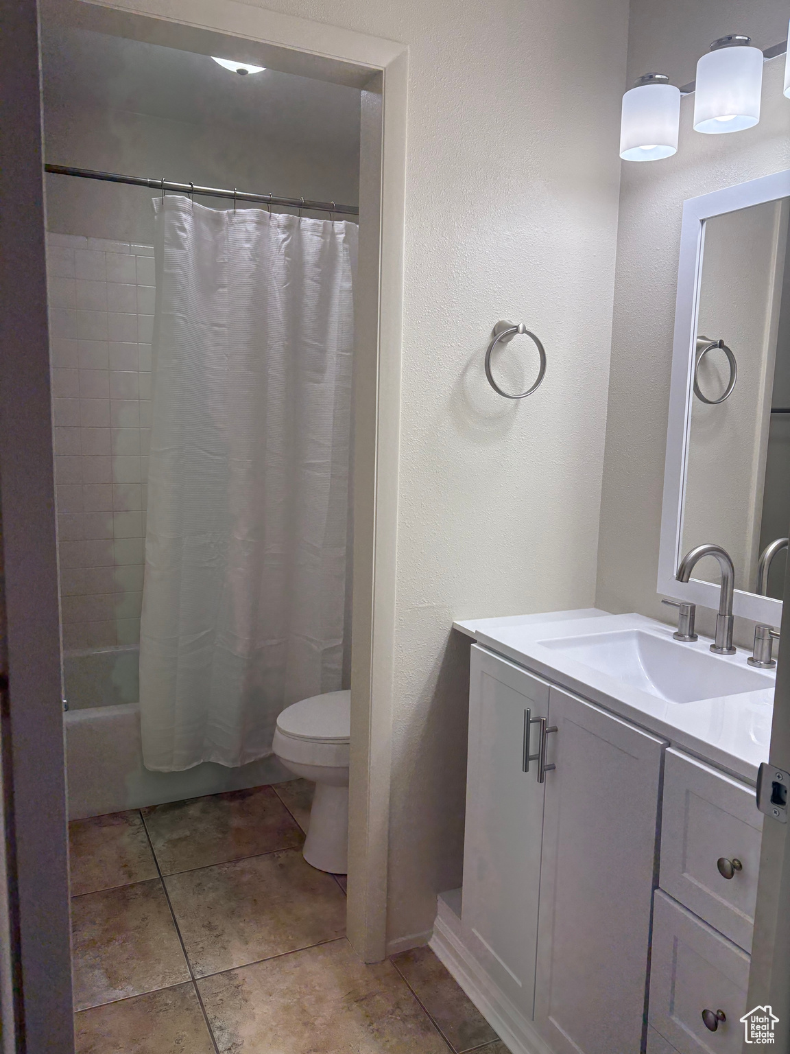 Full bathroom featuring vanity, shower / bath combo, tile patterned floors, and toilet