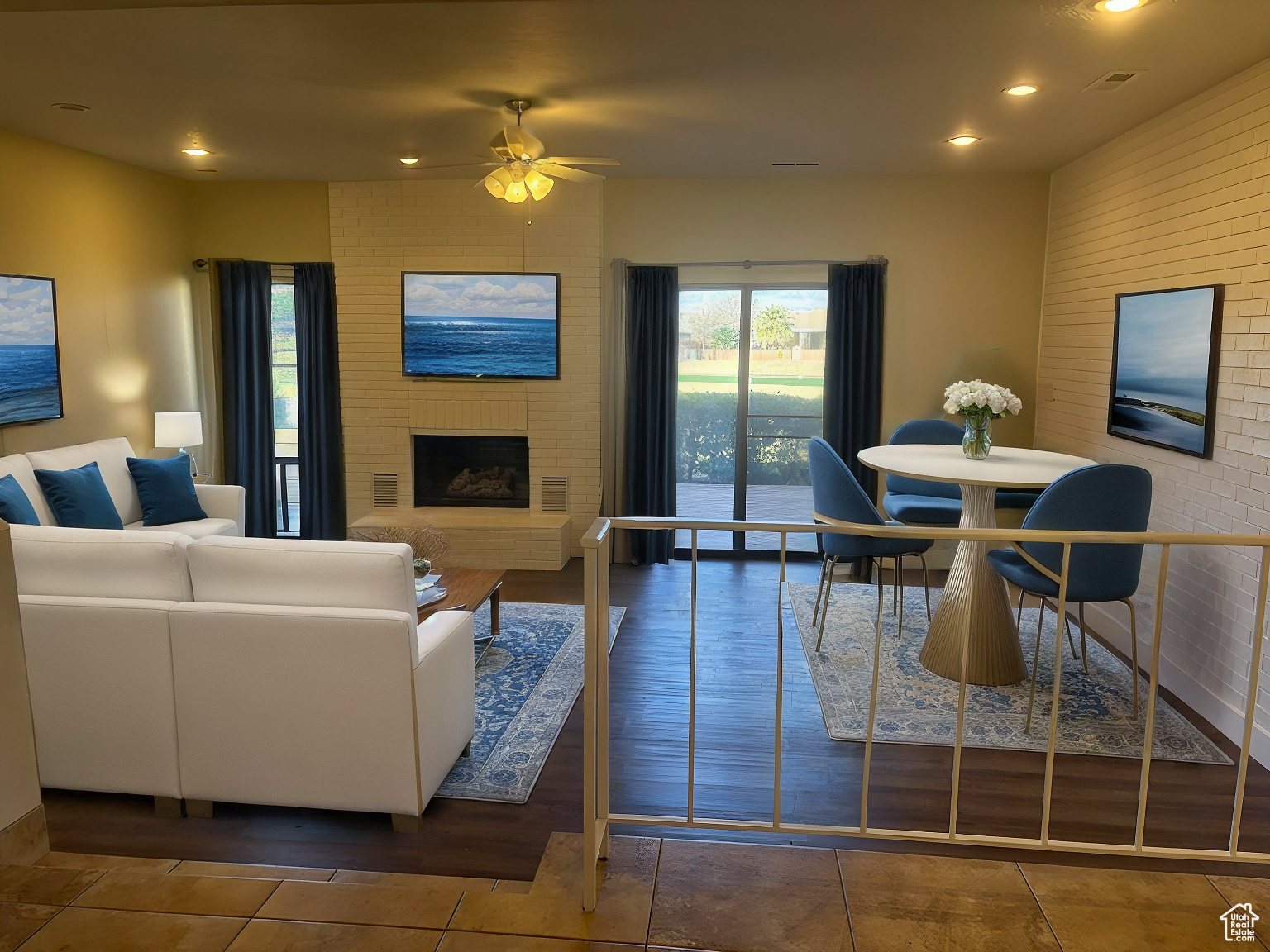 Living room with ceiling fan, a brick fireplace, and dark tile patterned floors