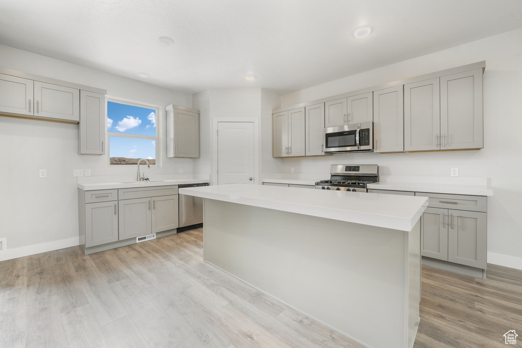 Kitchen with sink, gray cabinets, stainless steel appliances, and a center island