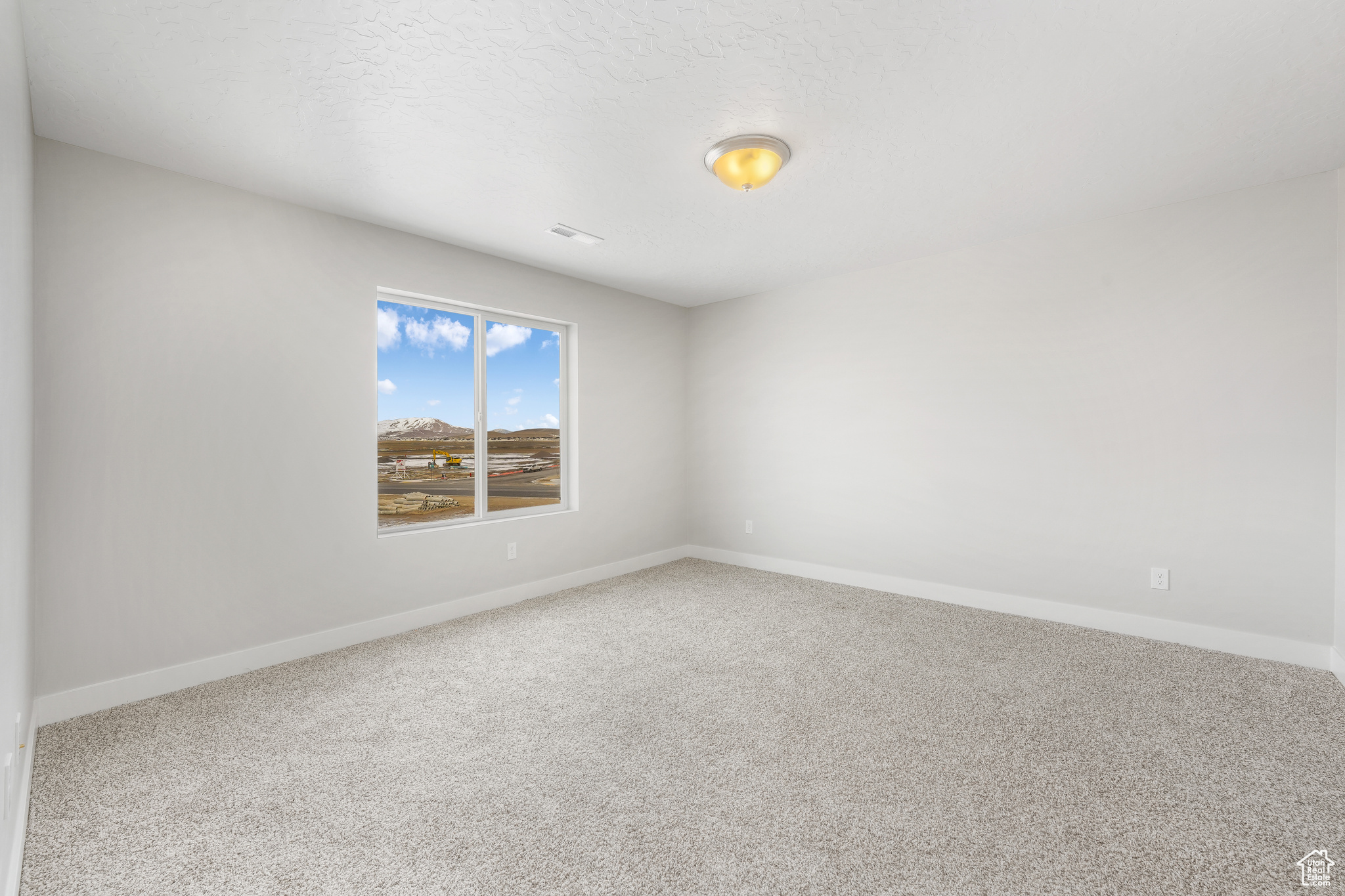 Carpeted empty room featuring a textured ceiling