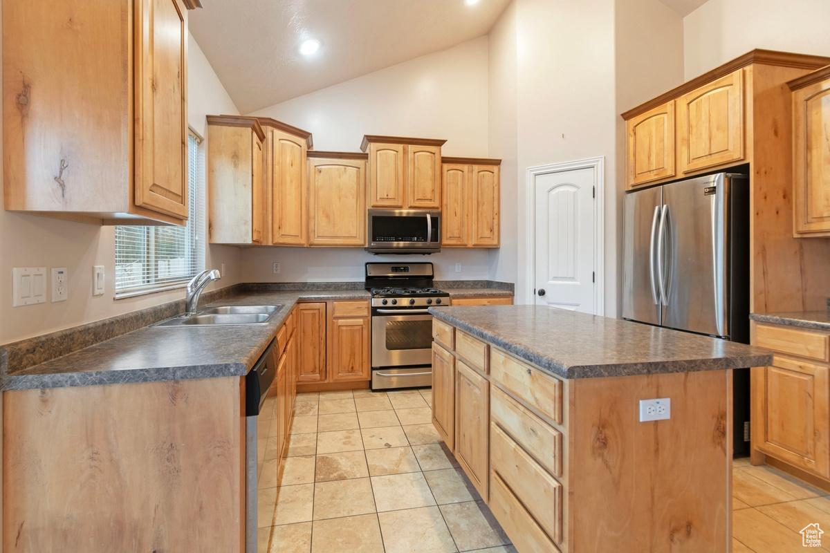 Kitchen with sink, light tile patterned floors, appliances with stainless steel finishes, high vaulted ceiling, and a center island