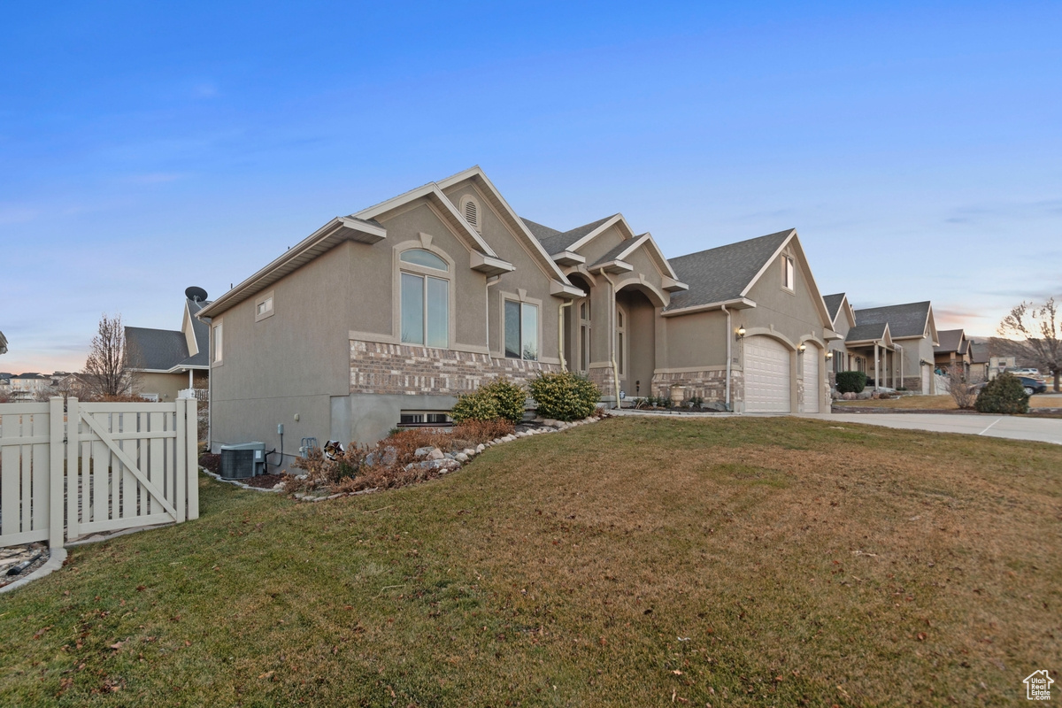 View of front of home featuring a yard, a garage, and central AC