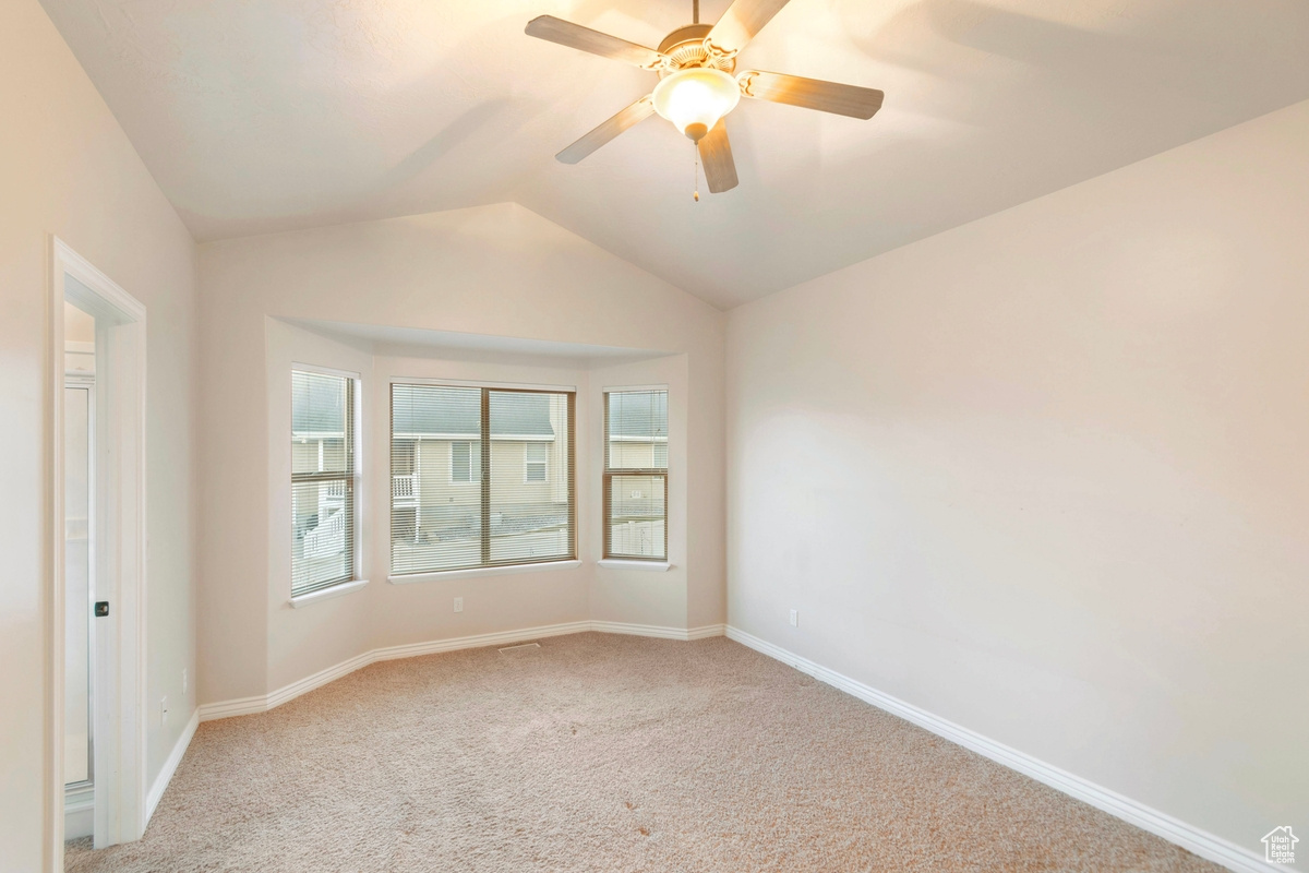 Spare room with vaulted ceiling, light colored carpet, and ceiling fan