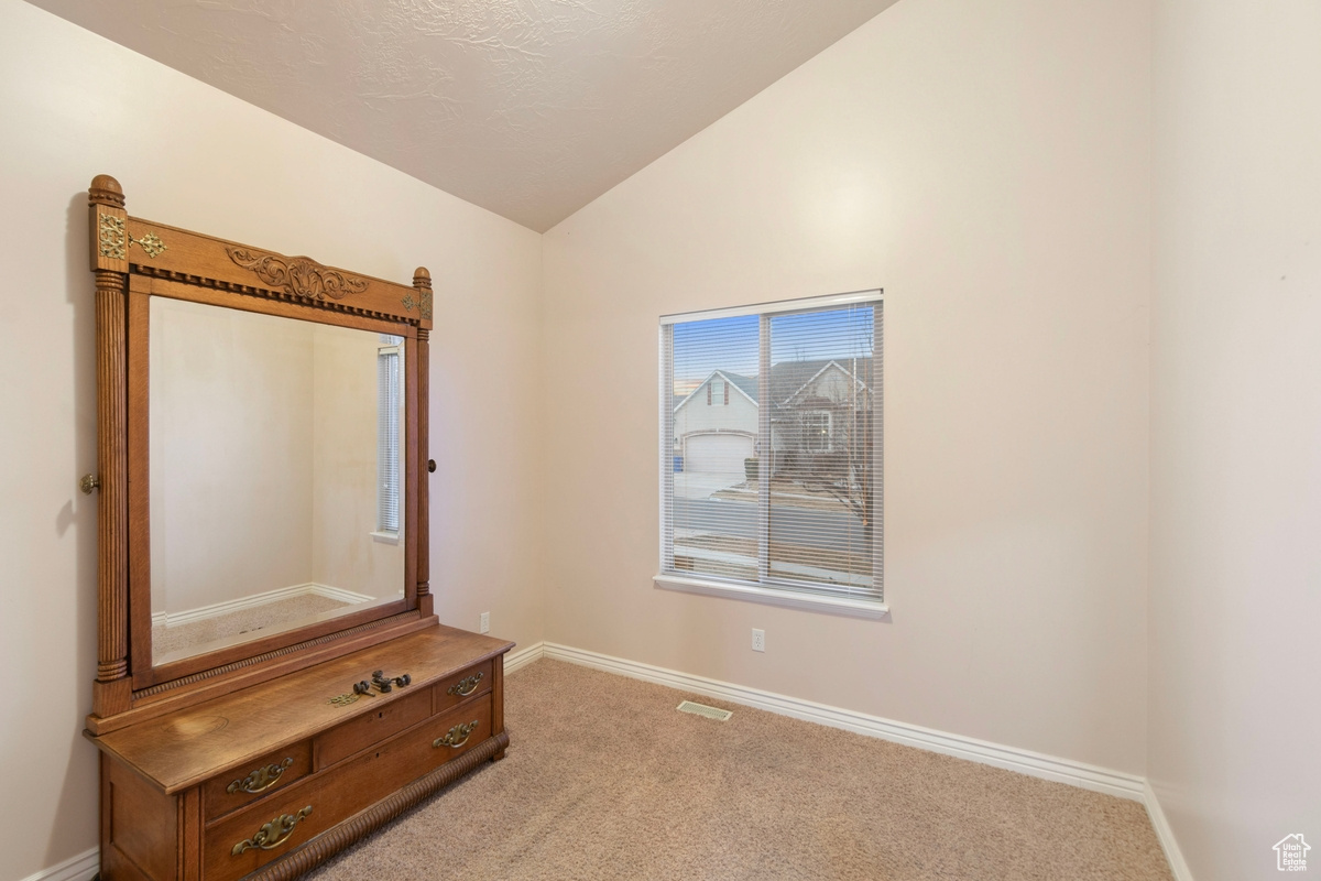 Unfurnished bedroom featuring lofted ceiling and light carpet