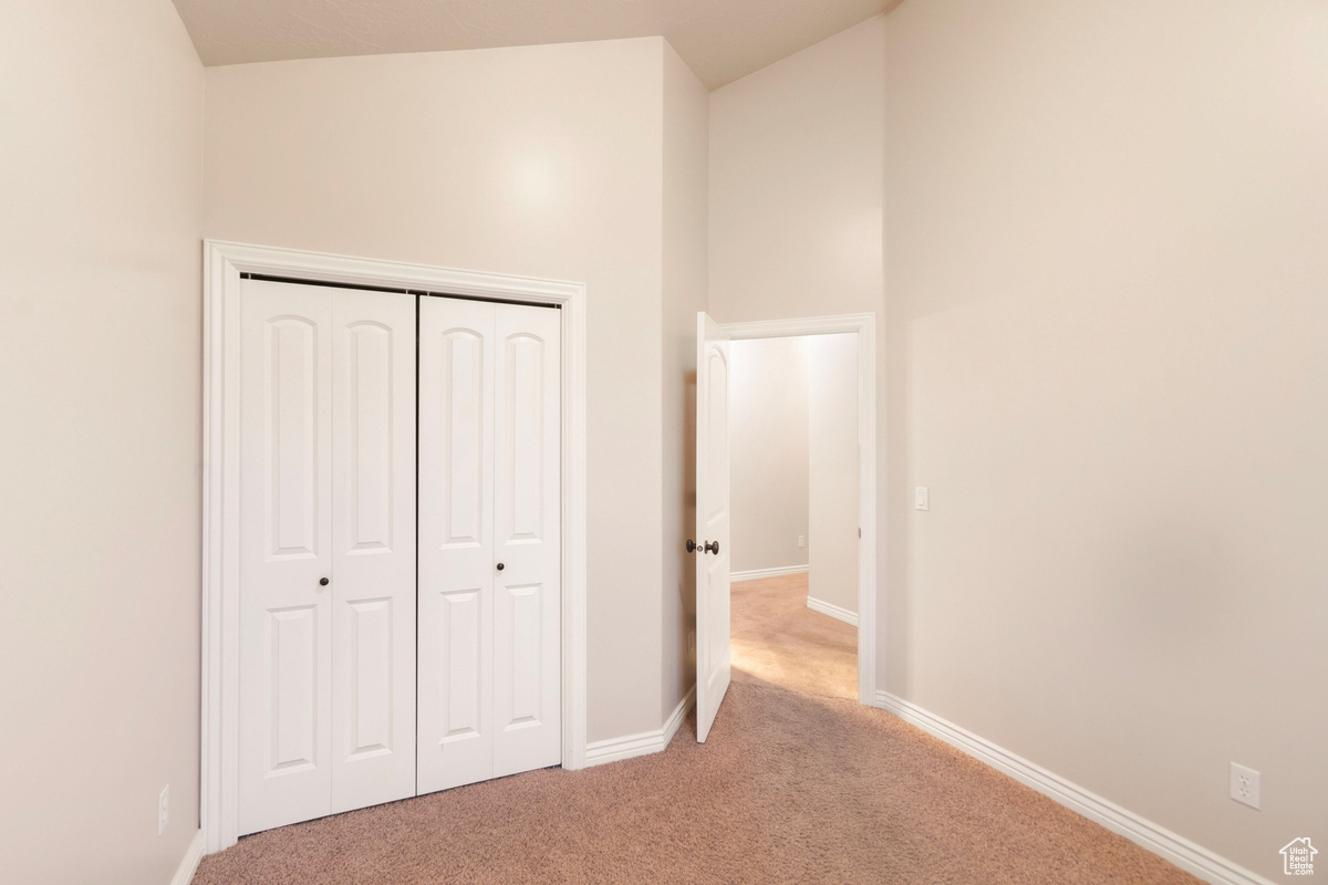 Unfurnished bedroom featuring light carpet and a closet