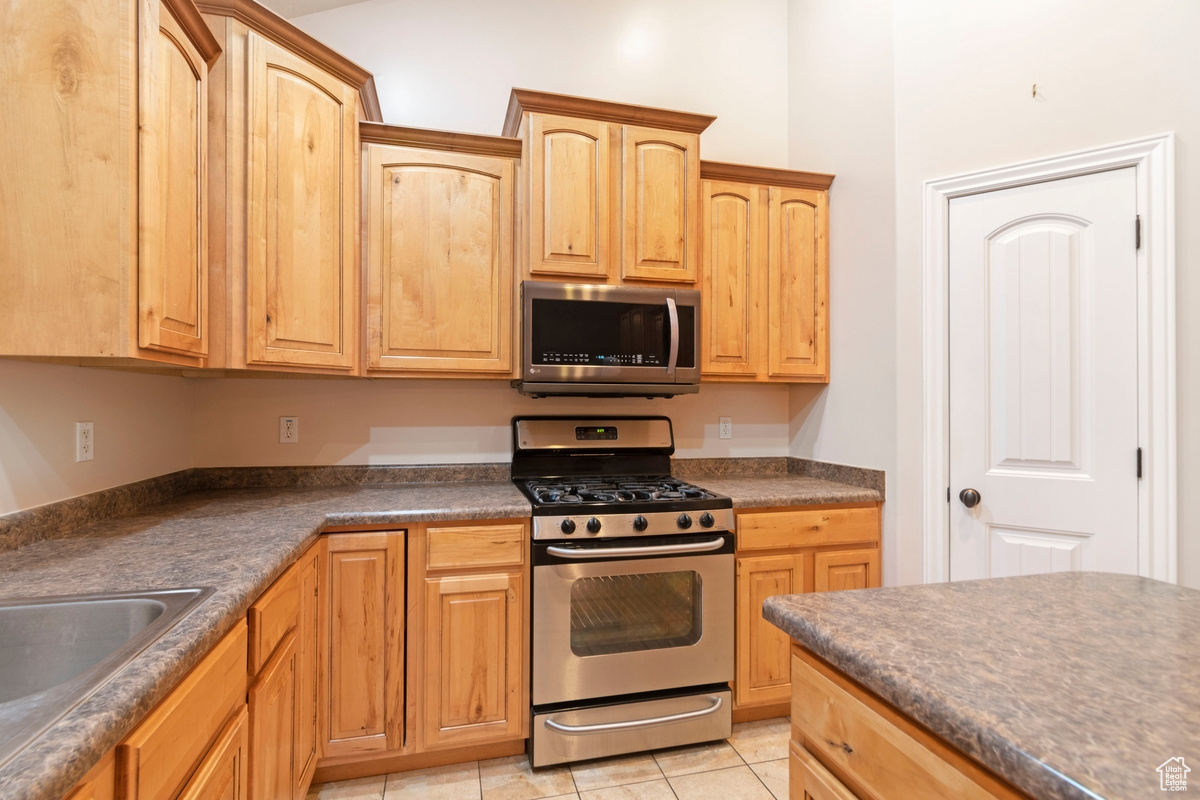 Kitchen with stainless steel appliances, sink, and light tile patterned floors