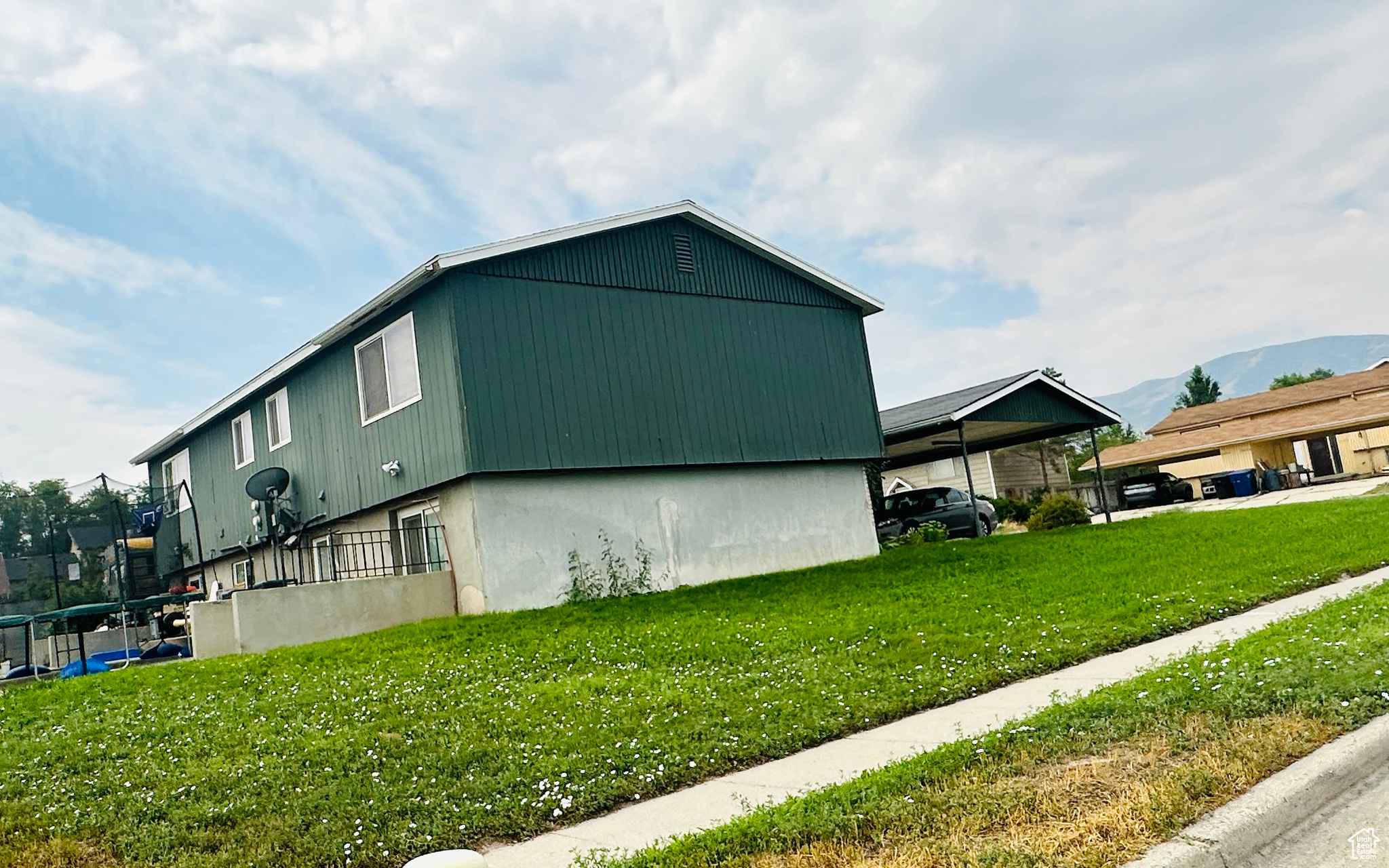 View of home's exterior featuring a mountain view, a yard, and a carport