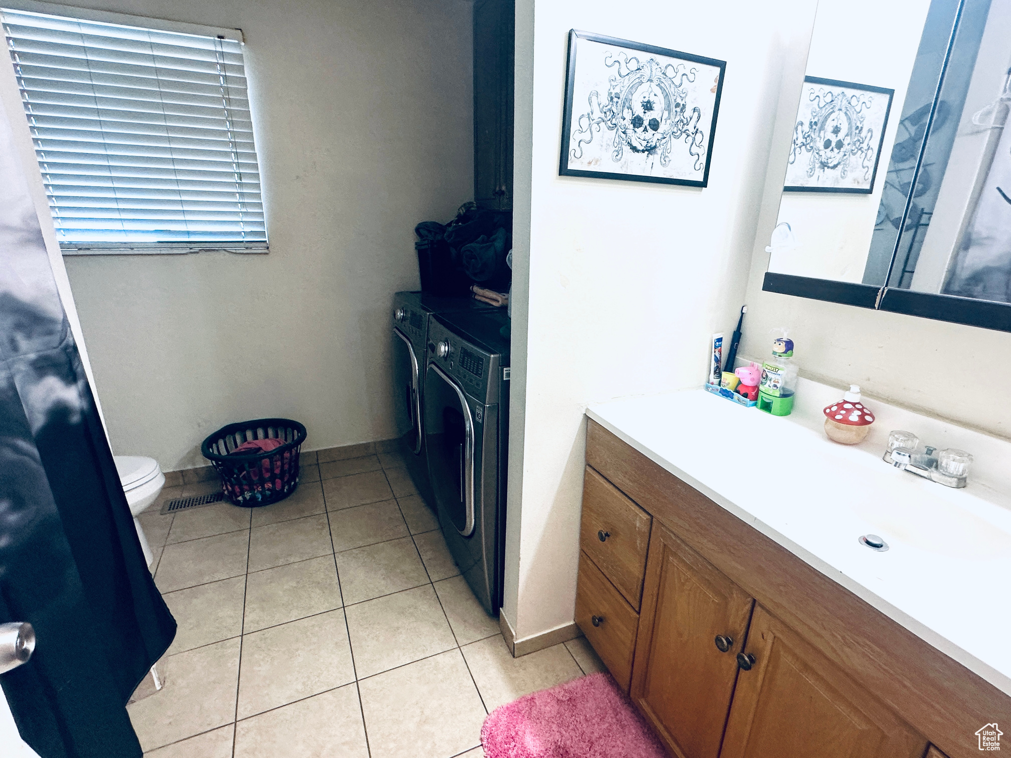 Bathroom with tile patterned floors, toilet, washer and clothes dryer, and vanity