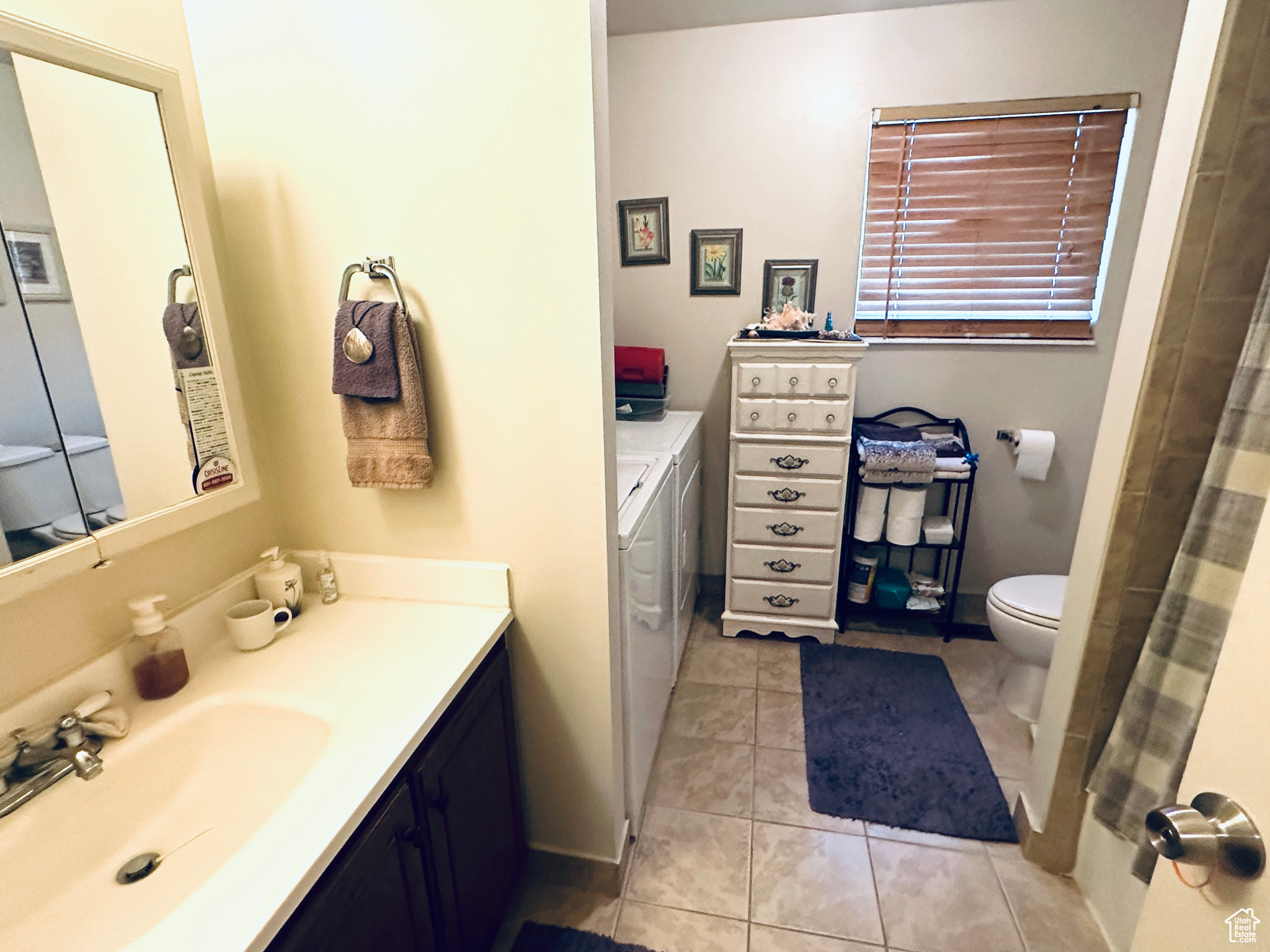 Bathroom featuring tile patterned floors, toilet, washer and clothes dryer, and vanity