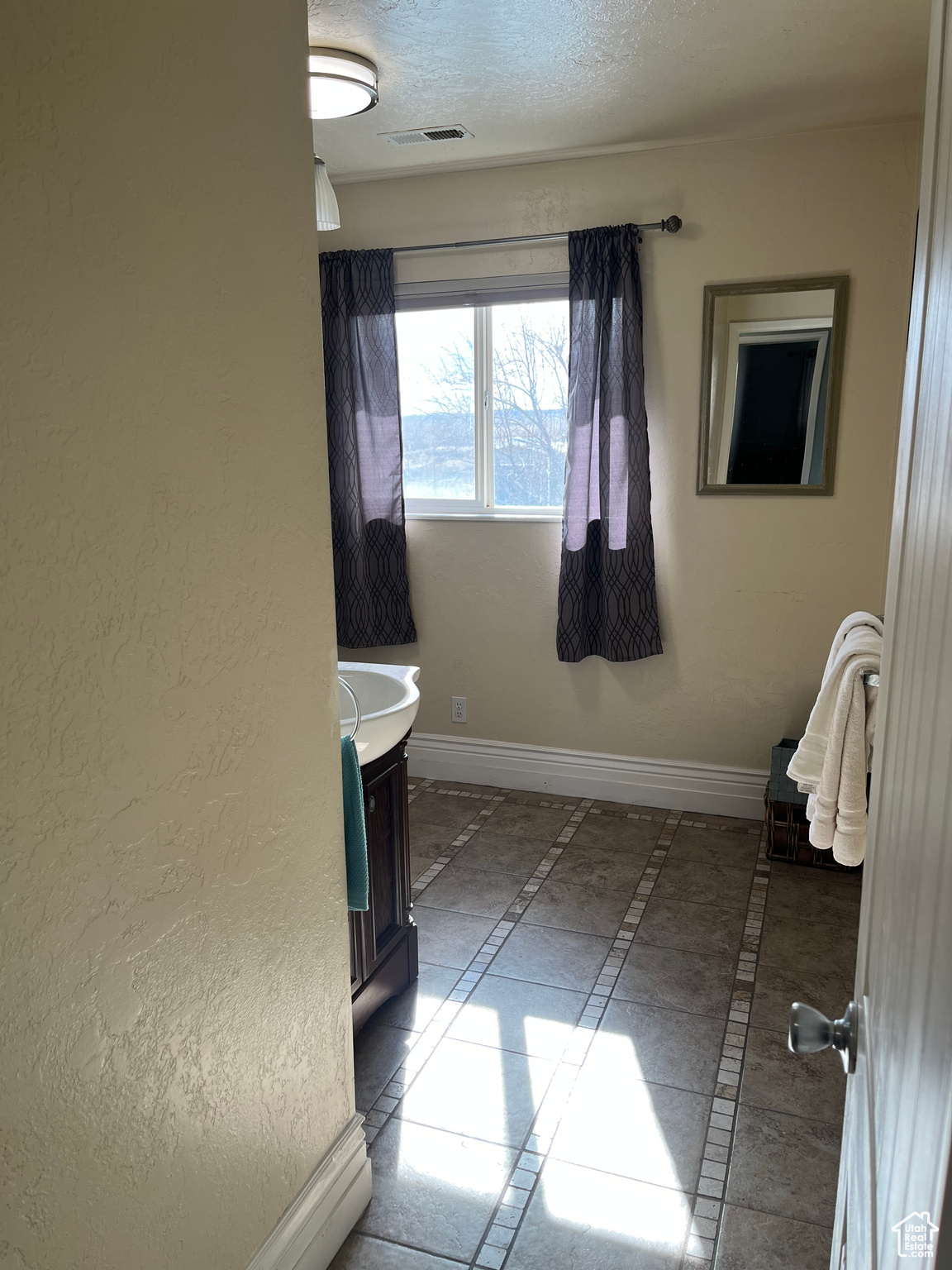 Bathroom with tile patterned flooring, vanity, and a textured ceiling