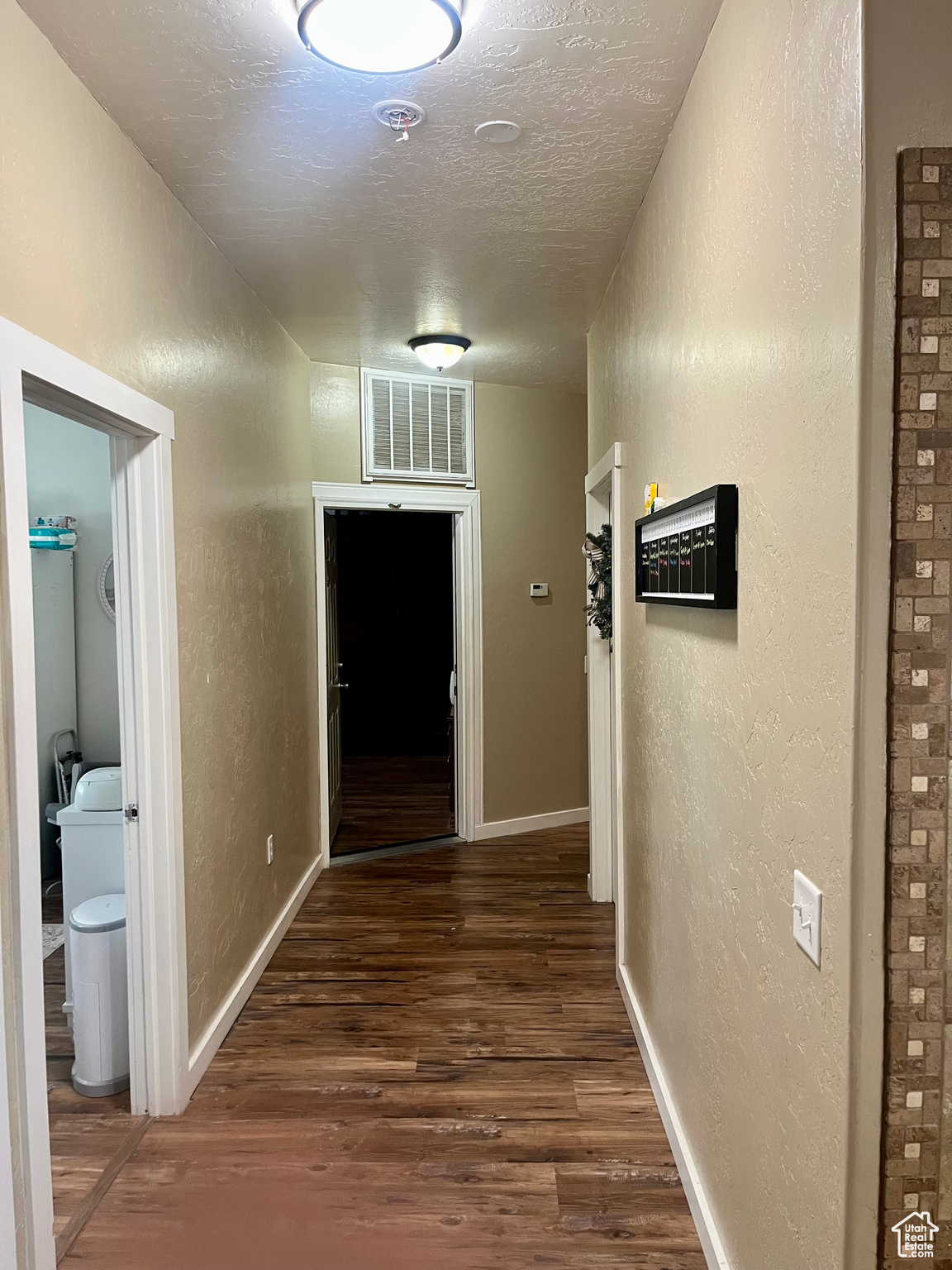 Hallway with dark hardwood / wood-style floors and a textured ceiling