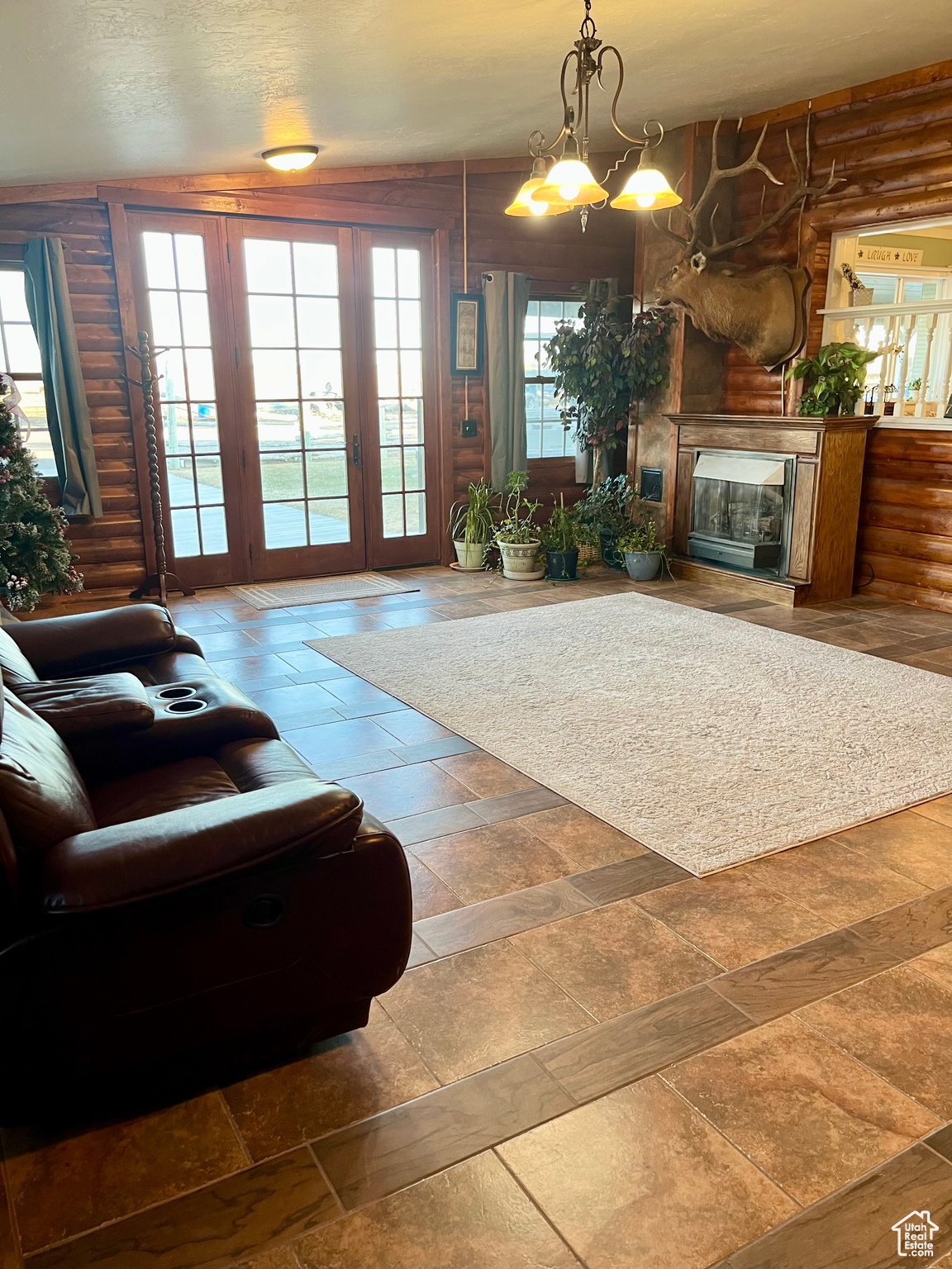 Large Living room featuring log walls, plenty of natural light, and a portable fireplace.