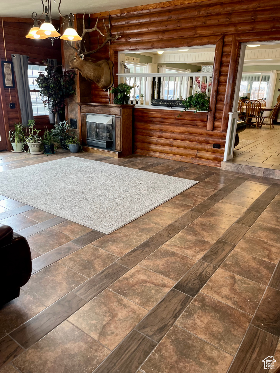 Unfurnished living room with log walls and a notable chandelier