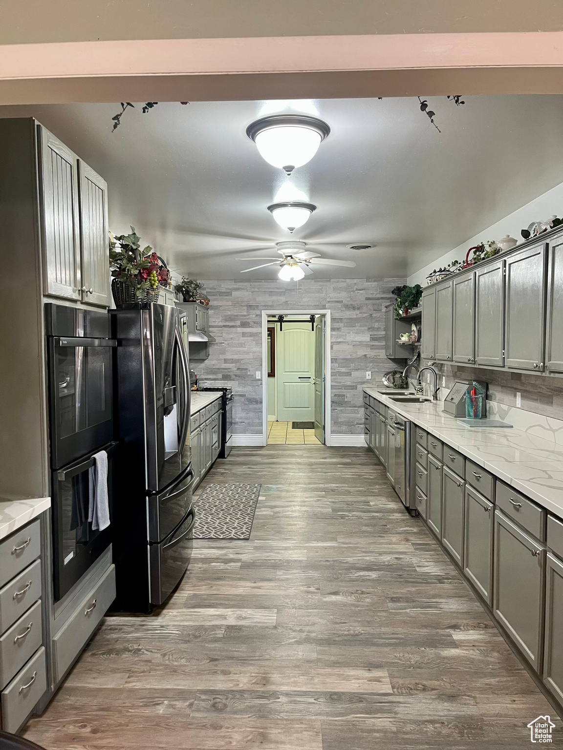 Kitchen with sink, wood-type flooring, stainless steel fridge, double oven, and a barn door