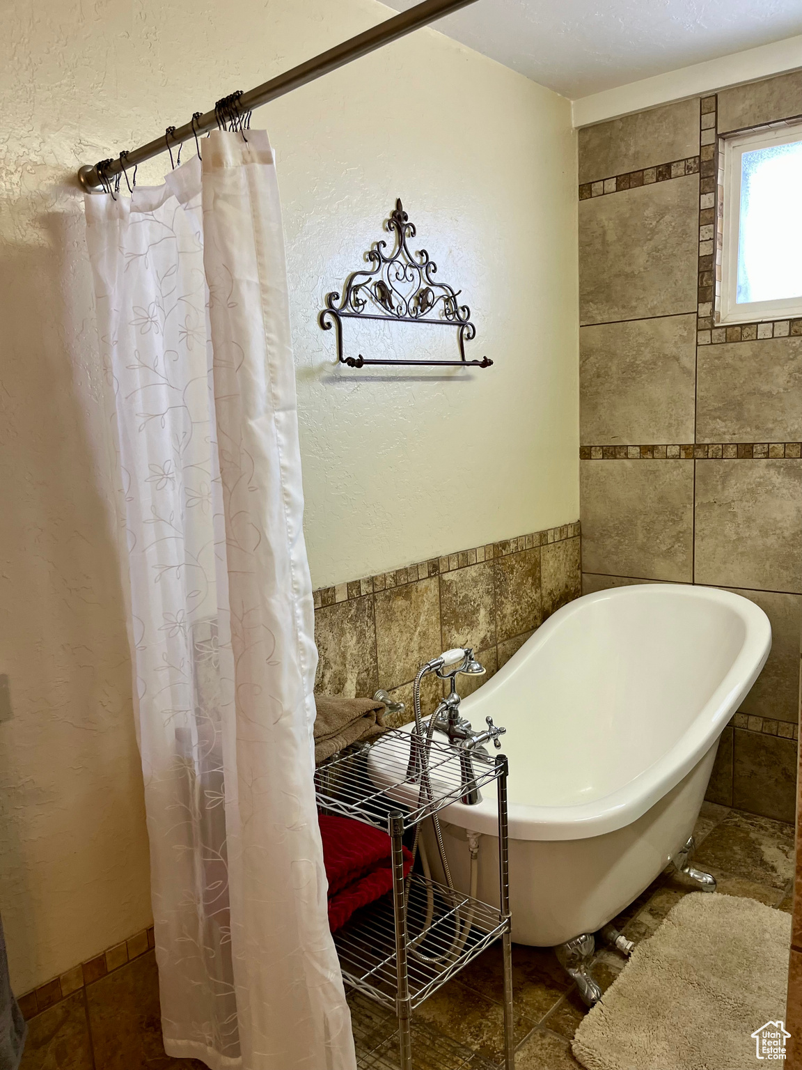 Bathroom with tile walls, a bathtub, and tile patterned floors