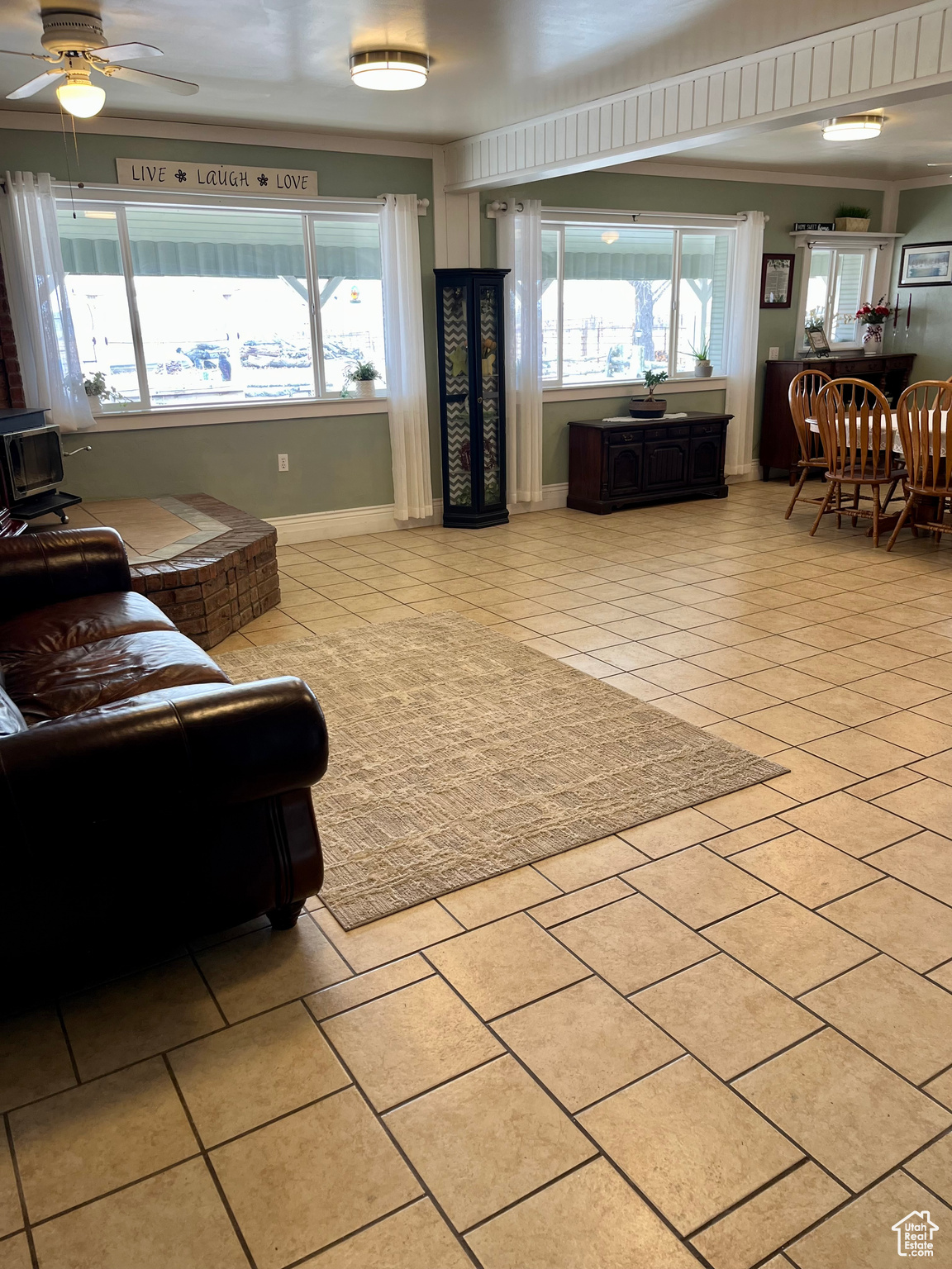 Living room featuring ceiling fan, ornamental molding, and light tile patterned floors
