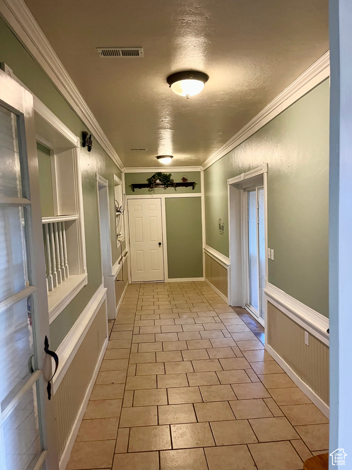 Hall with crown molding, light tile patterned flooring, and a textured ceiling