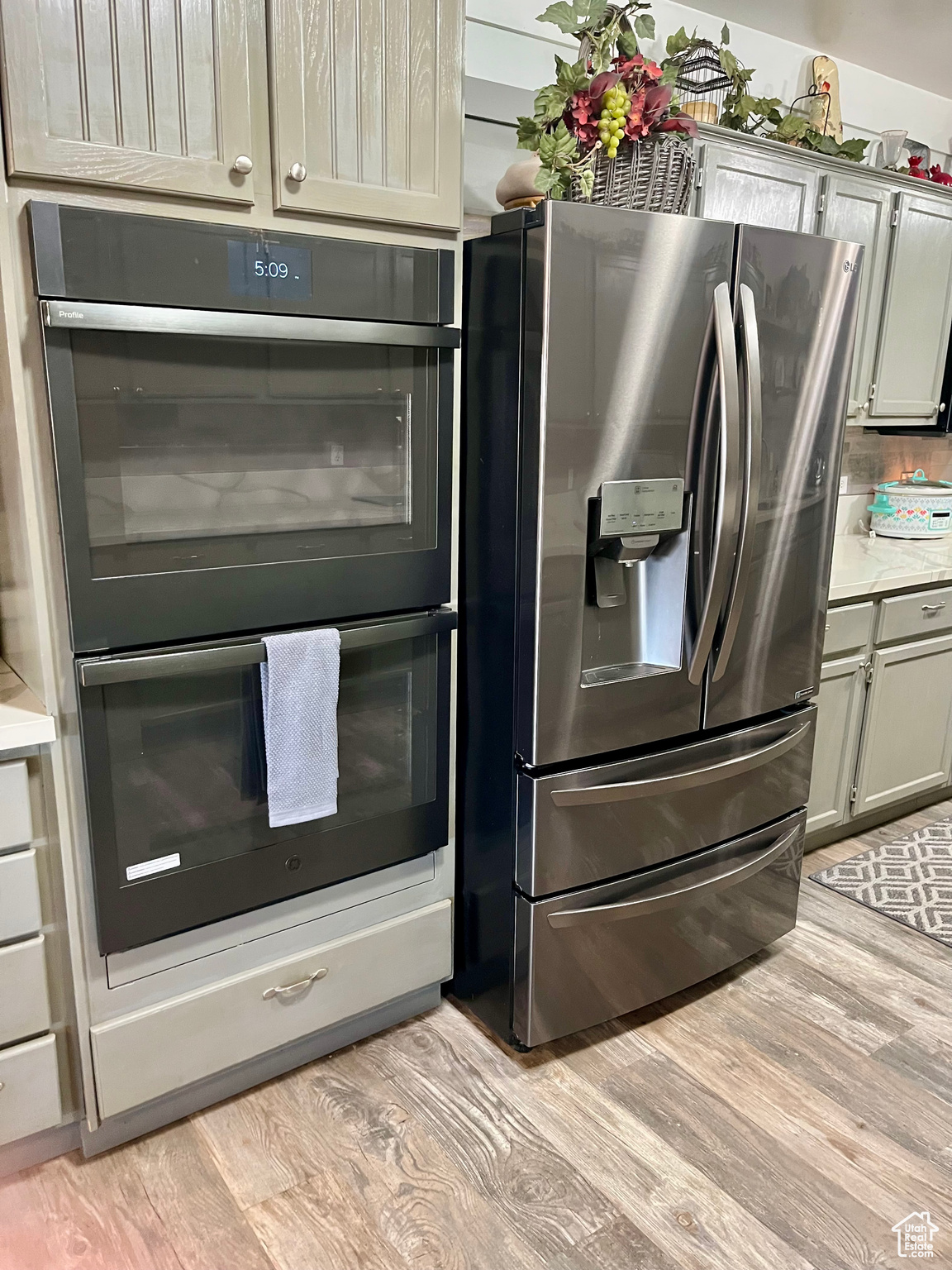 Kitchen with black double oven, stainless steel fridge, and light hardwood / wood-style flooring
