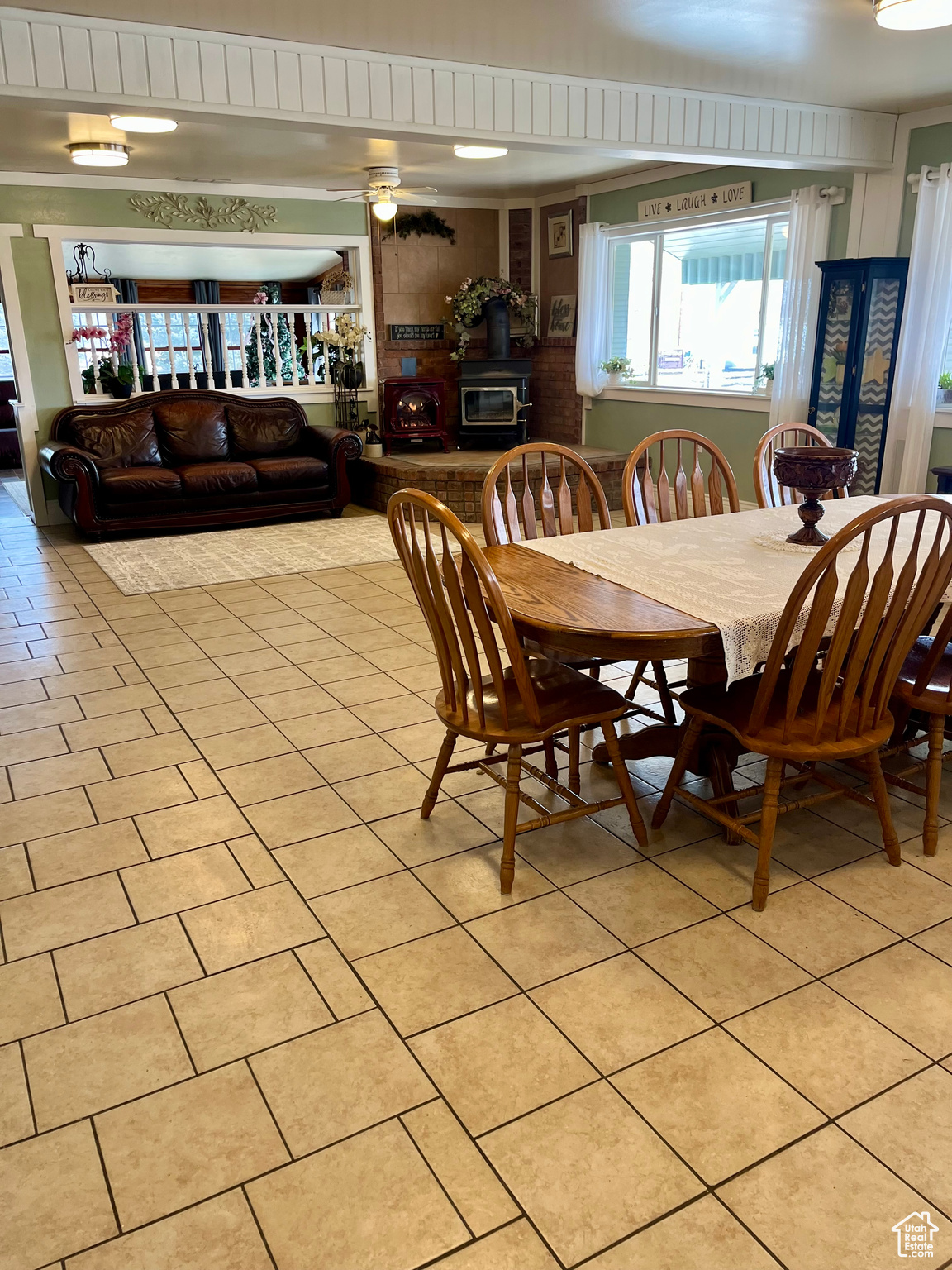 Dining space with light tile patterned floors, ceiling fan, and a wood stove