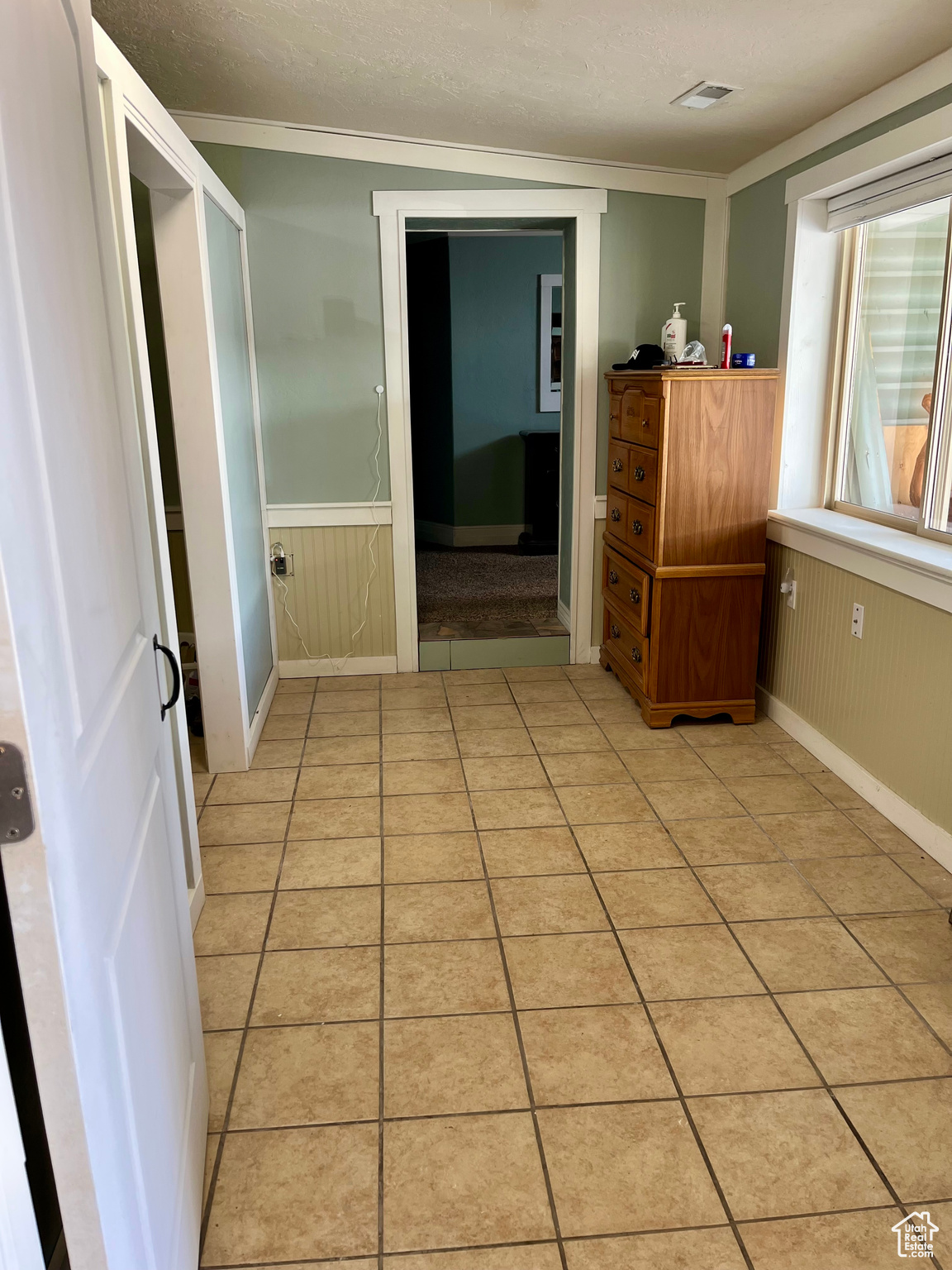 Interior space featuring ornamental molding, a textured ceiling, and light tile patterned floors