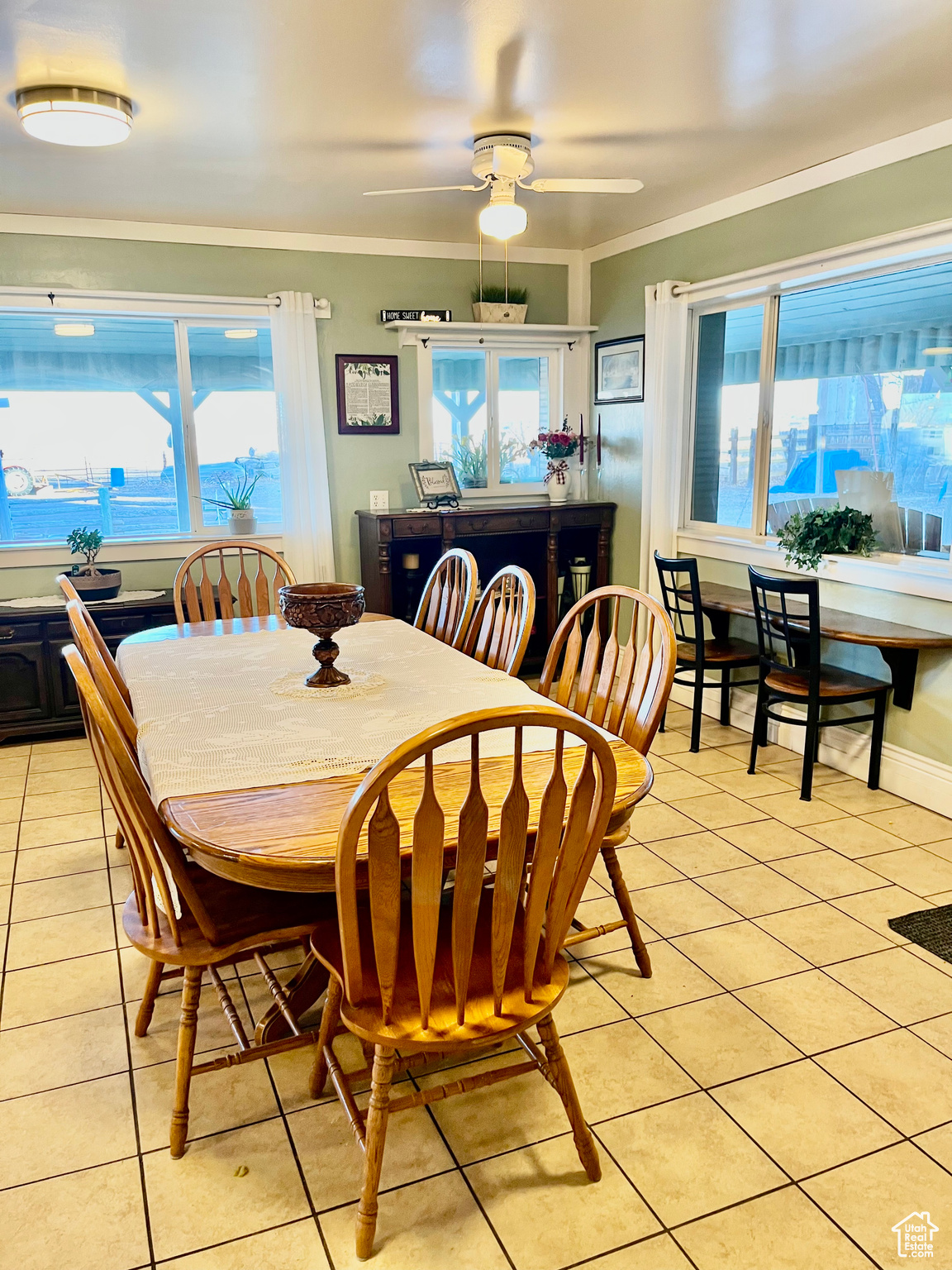 Tiled dining room featuring plenty of natural light, ornamental molding, and ceiling fan