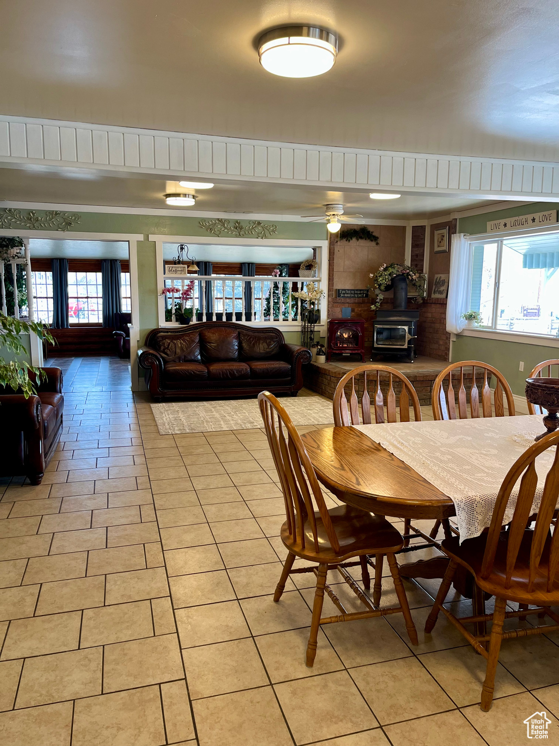 Dining space featuring light tile patterned floors, plenty of natural light, and a wood stove