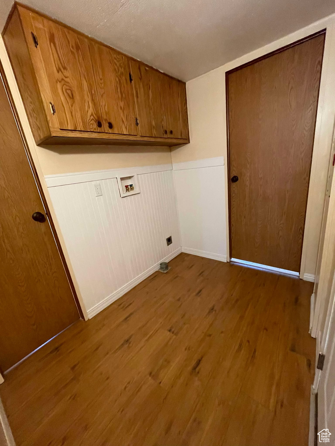 Laundry area featuring hookup for a washing machine, hardwood / wood-style flooring, and cabinets