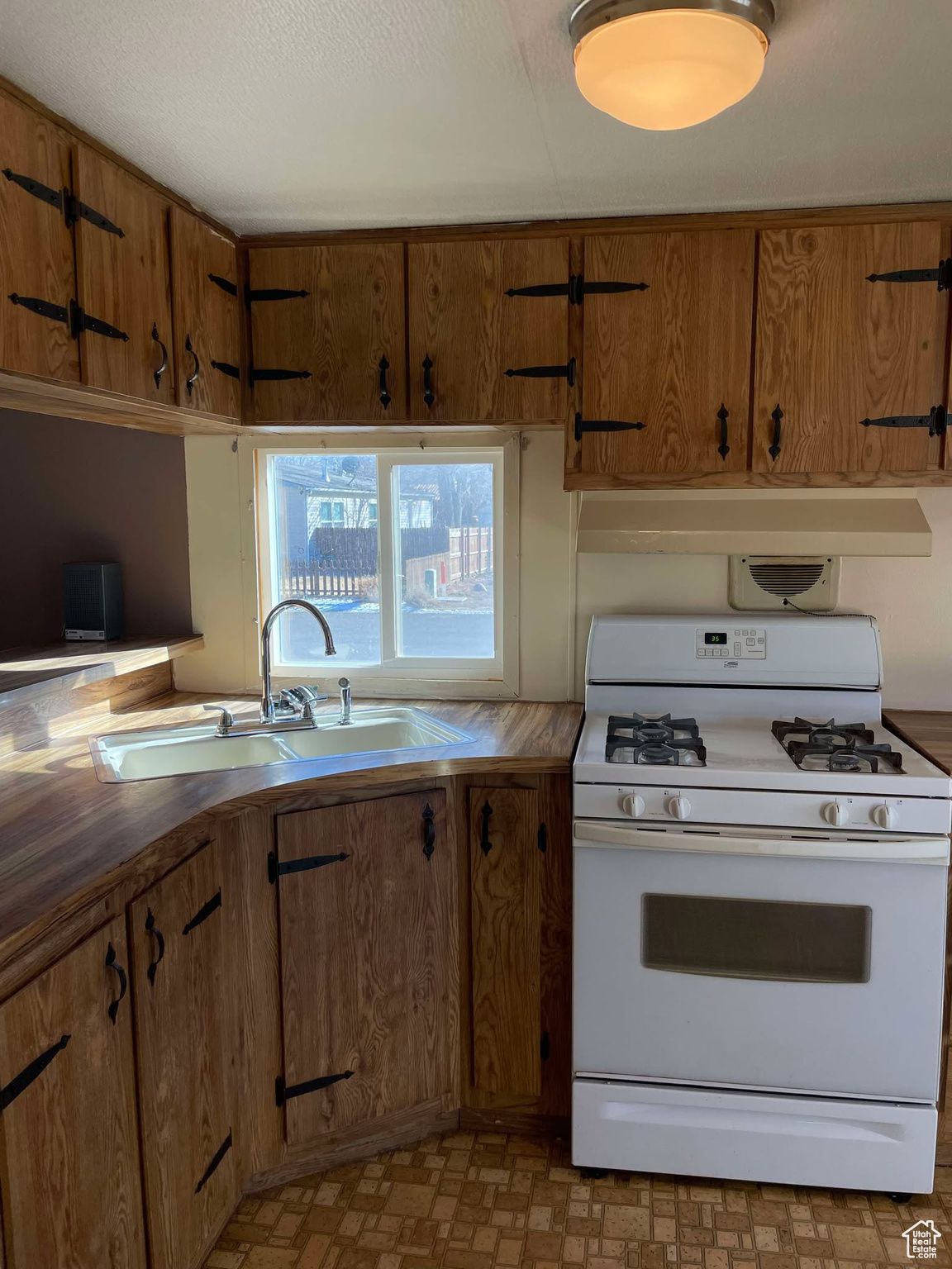 Kitchen with ventilation hood, white gas range, and sink