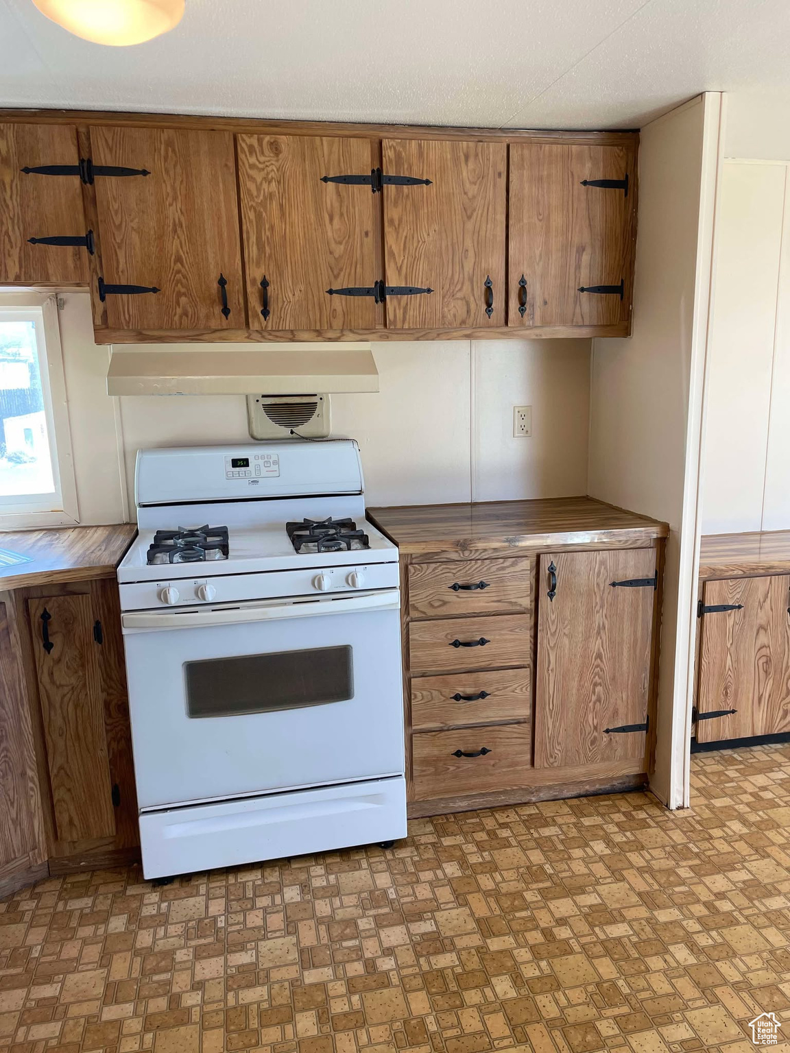 Kitchen with white range with gas cooktop and range hood