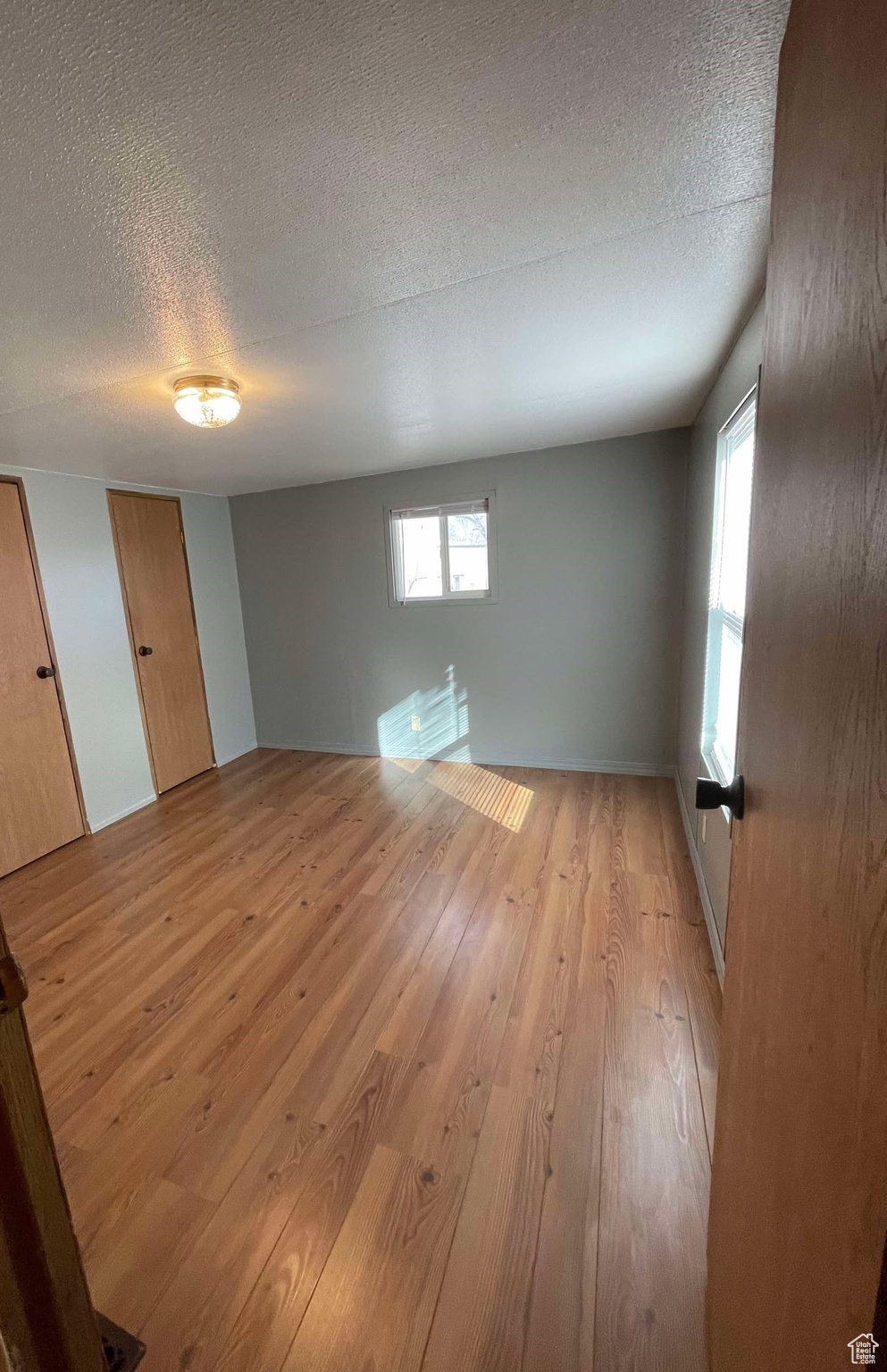 Unfurnished room with light wood finished floors and a textured ceiling