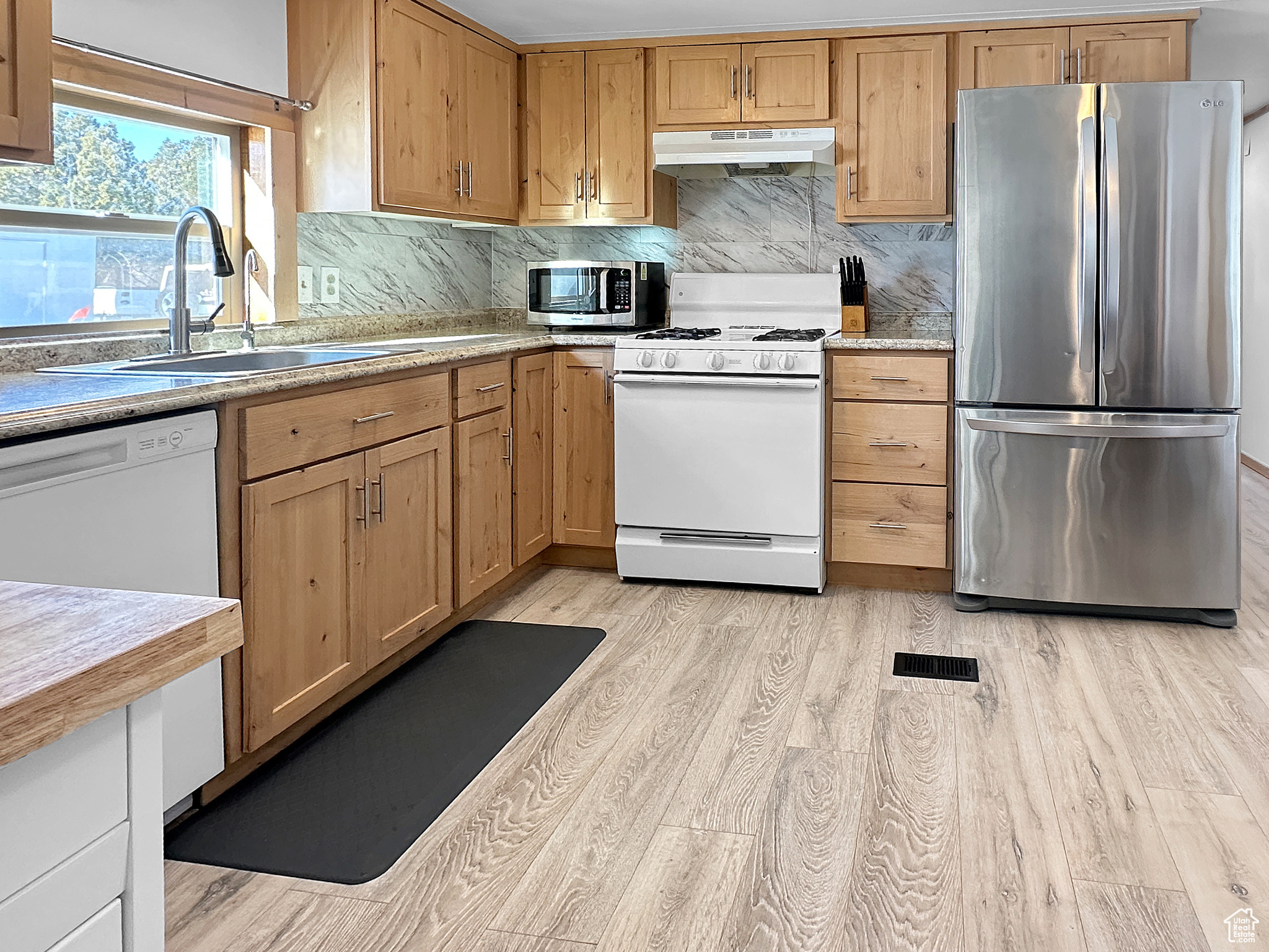 Kitchen featuring stainless steel appliances, tasteful backsplash, sink, and light wood-type flooring