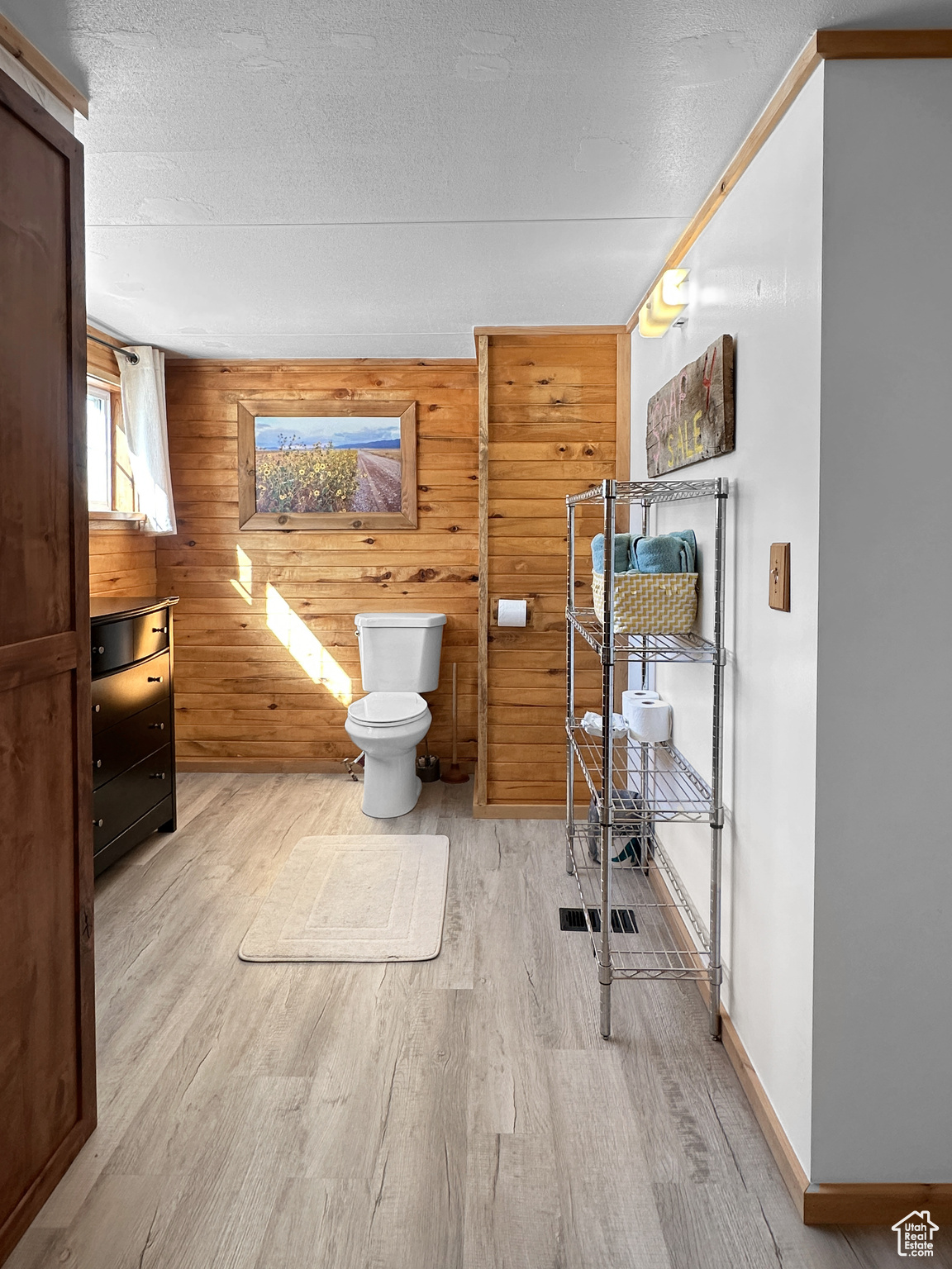 Bathroom featuring wood-type flooring, toilet, a textured ceiling, and wood walls
