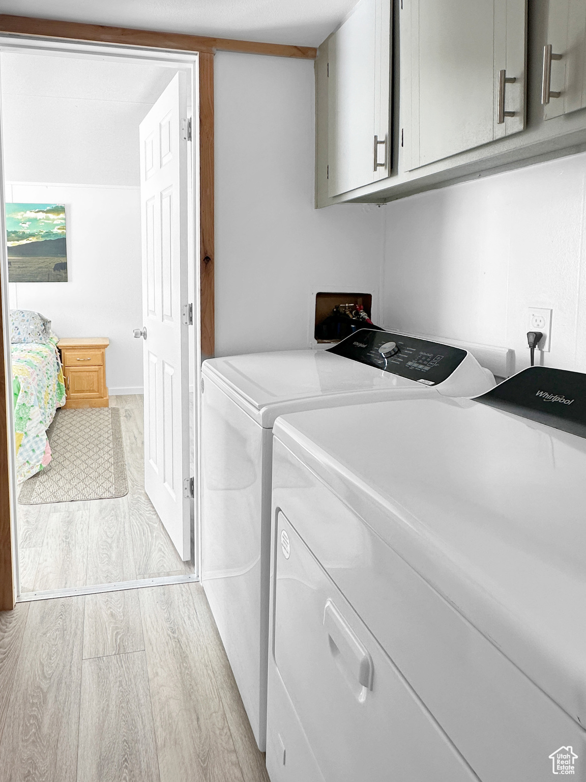 Clothes washing area featuring cabinets, light hardwood / wood-style floors, and washing machine and dryer