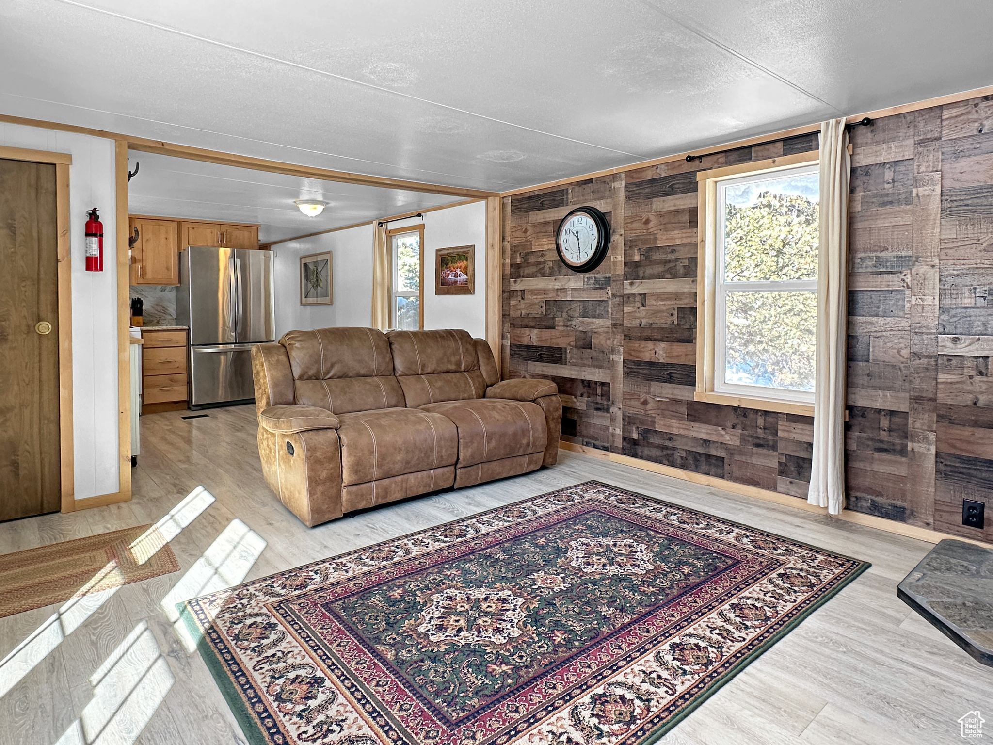 Living room featuring light hardwood / wood-style floors, a textured ceiling, and wood walls