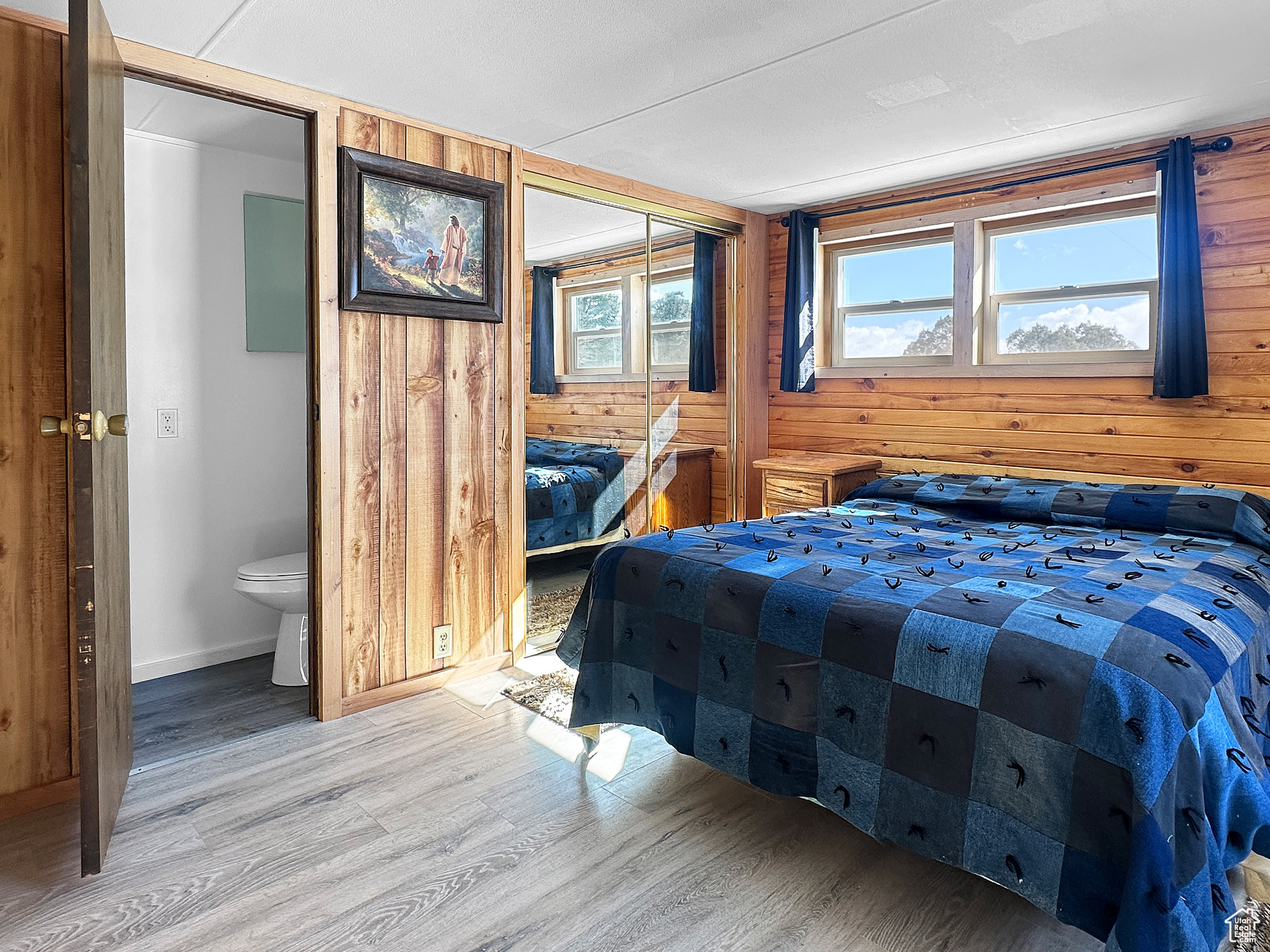 Bedroom with wood-type flooring, a closet, and wood walls