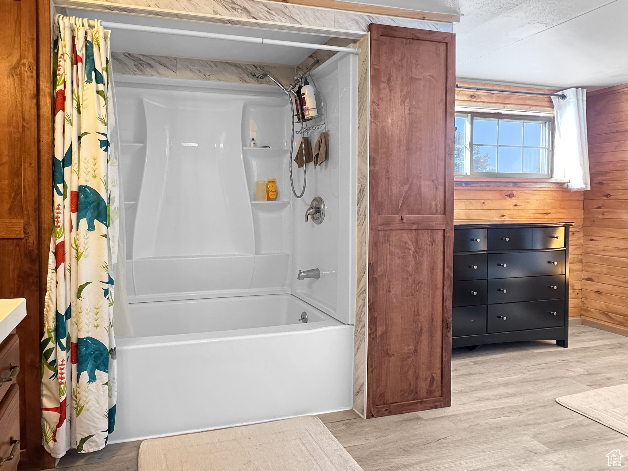 Bathroom with wooden walls, shower / tub combo, and hardwood / wood-style floors