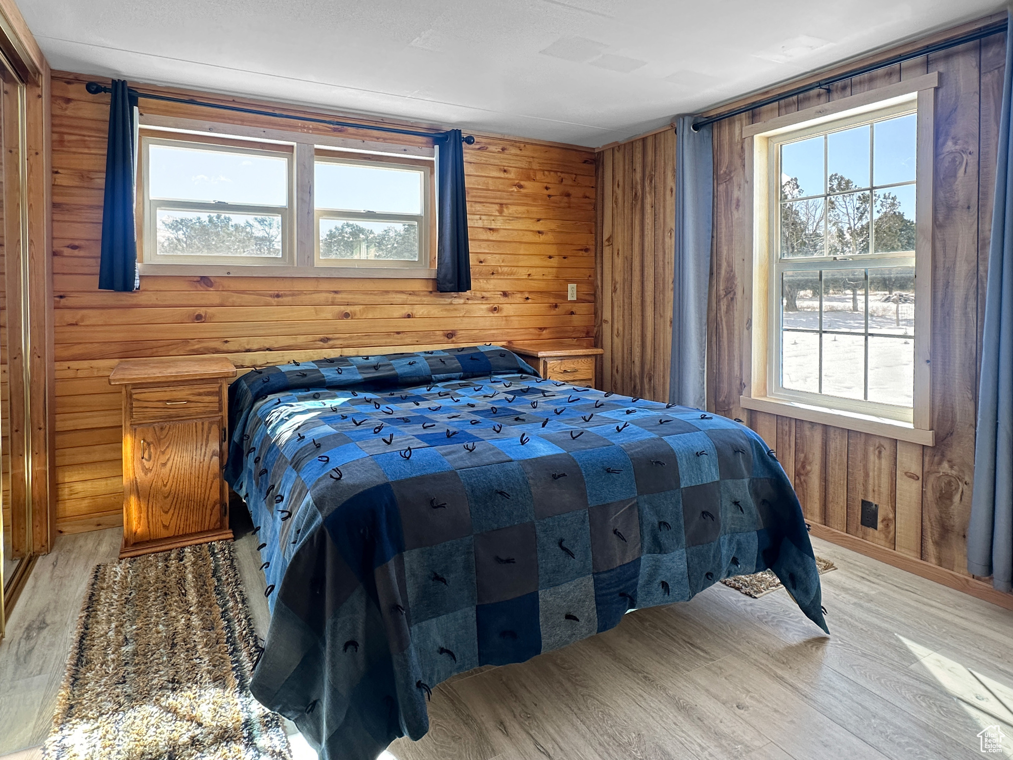 Bedroom with light hardwood / wood-style floors and wood walls