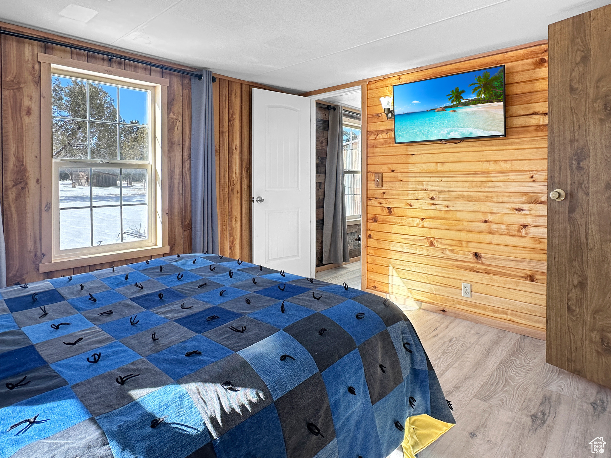 Unfurnished bedroom with multiple windows, wood-type flooring, and wood walls