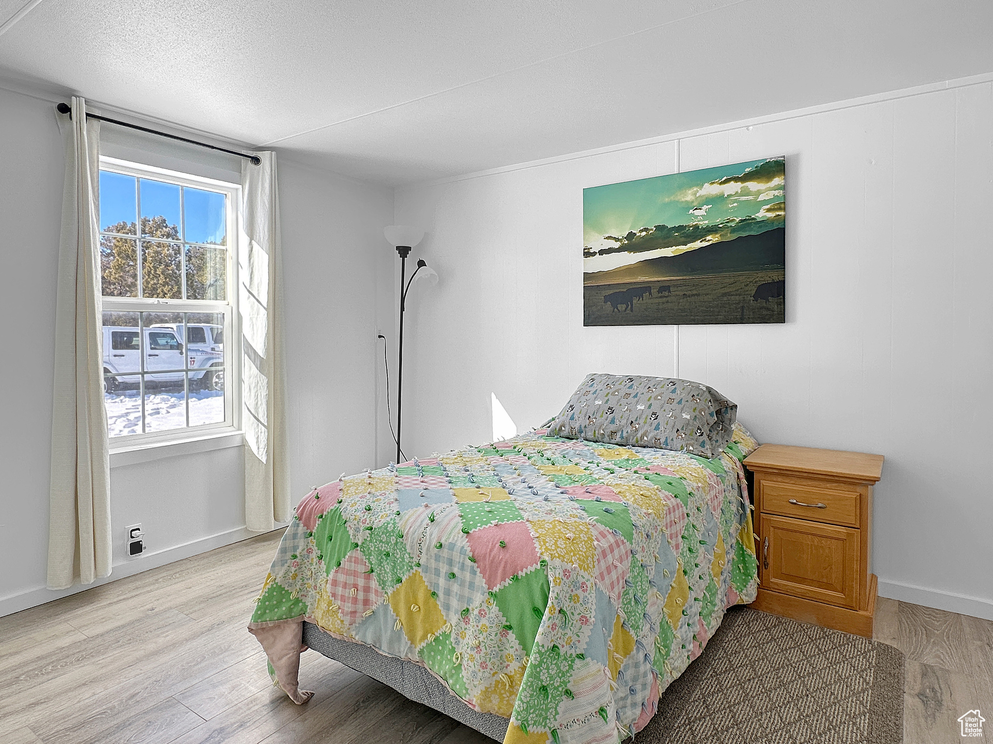 Bedroom with multiple windows, a textured ceiling, and light wood-type flooring