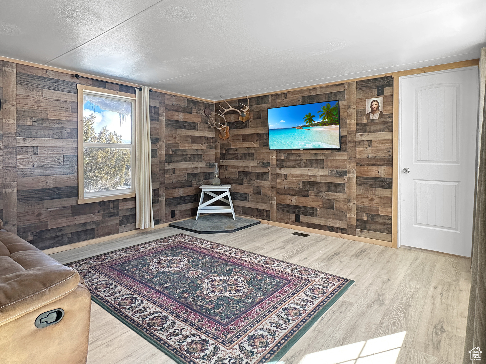 Sitting room with wood-type flooring, a textured ceiling, and wooden walls