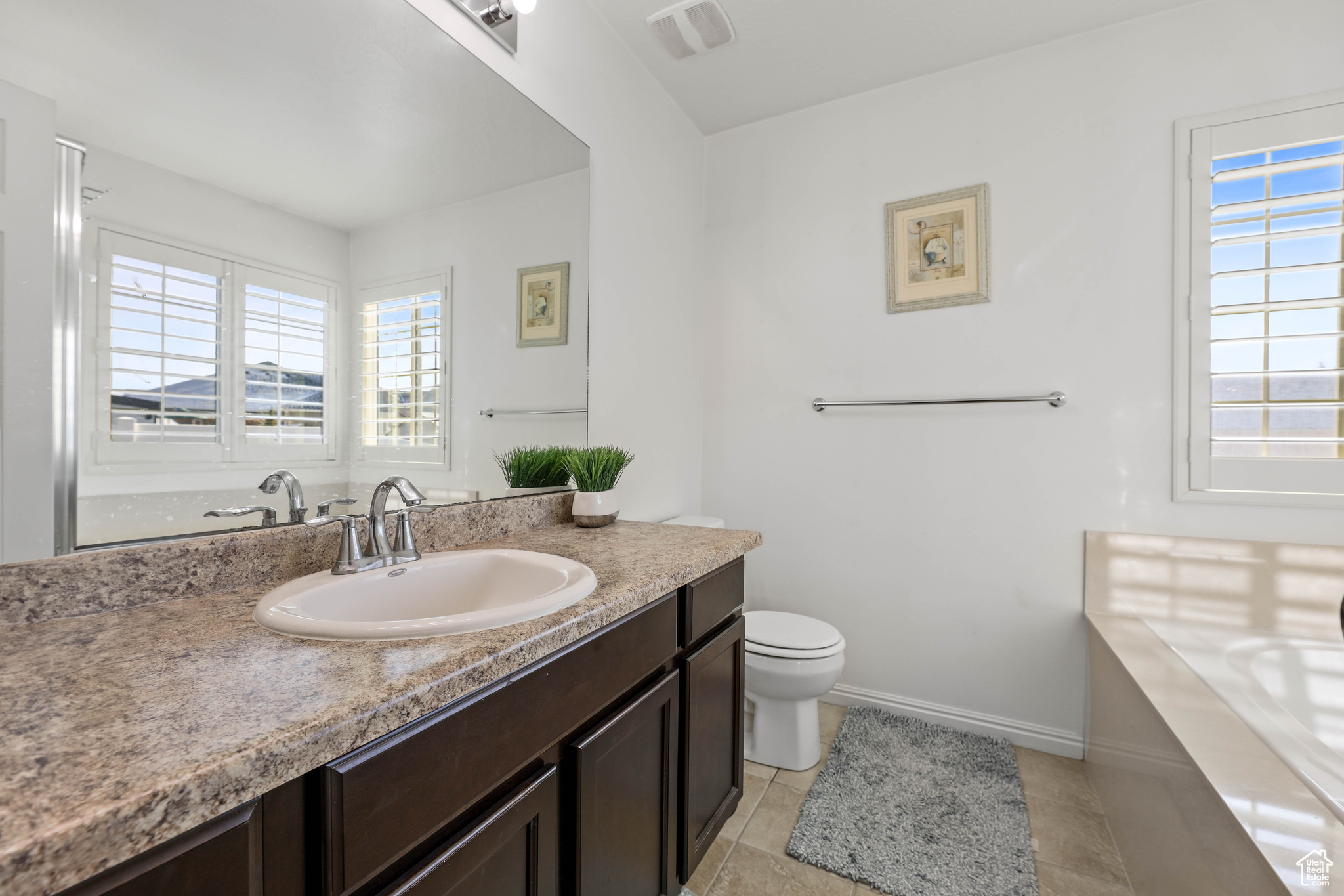 Bathroom with vanity, plenty of natural light, tile patterned floors, and toilet