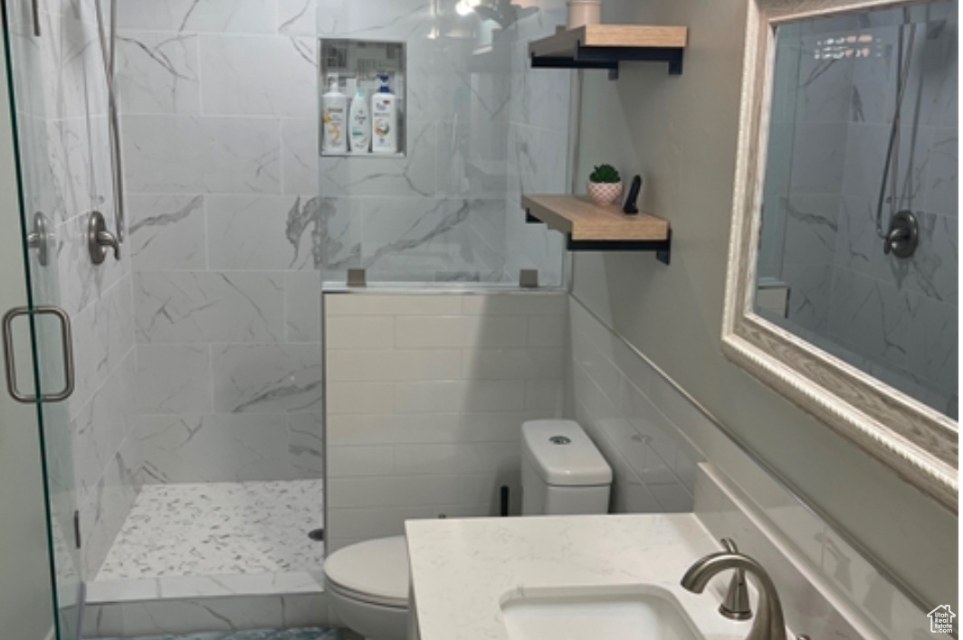 Bathroom with vanity, a shower with door, and toilet