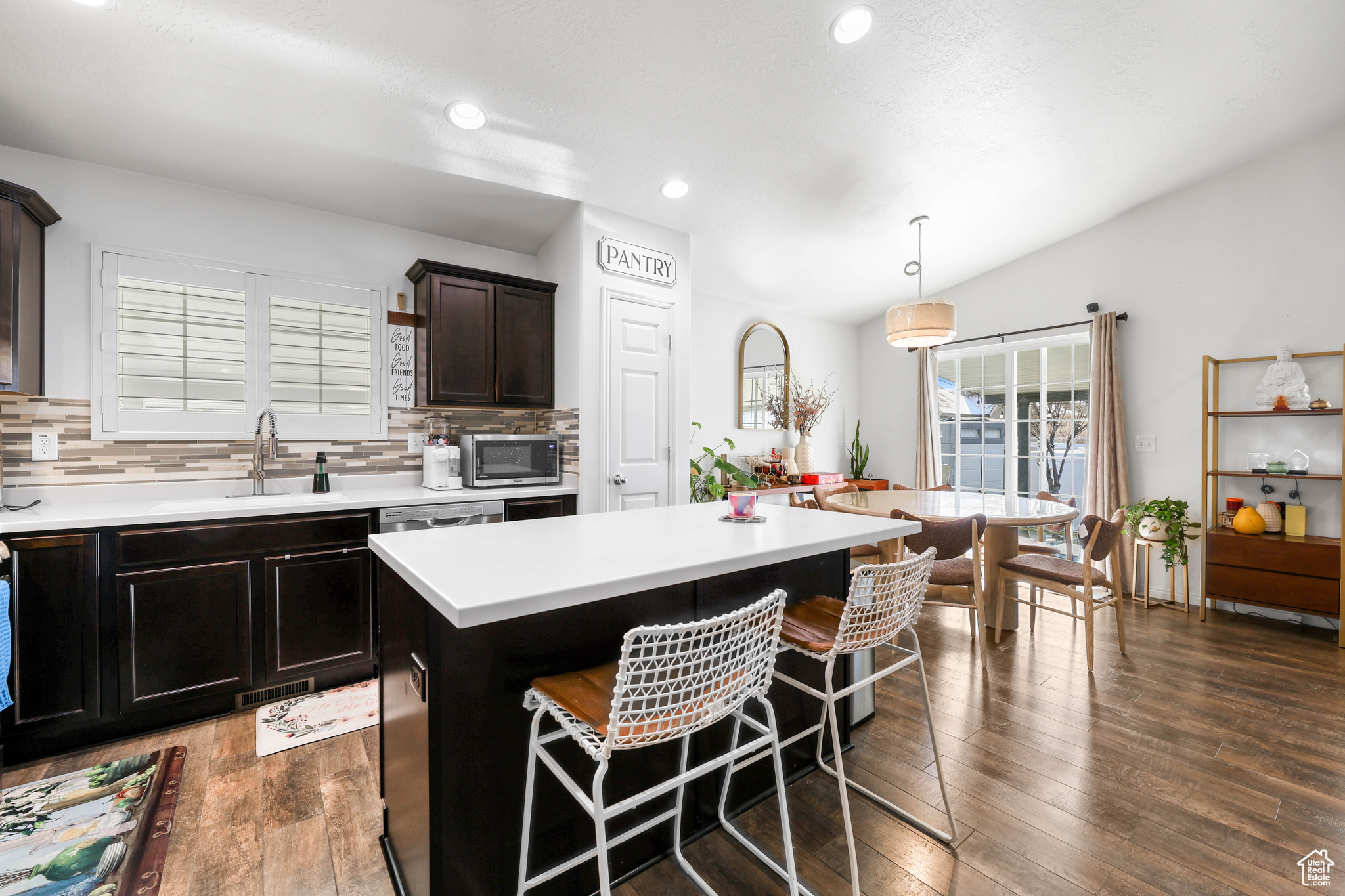 Kitchen with a kitchen island, sink, hanging light fixtures, and backsplash