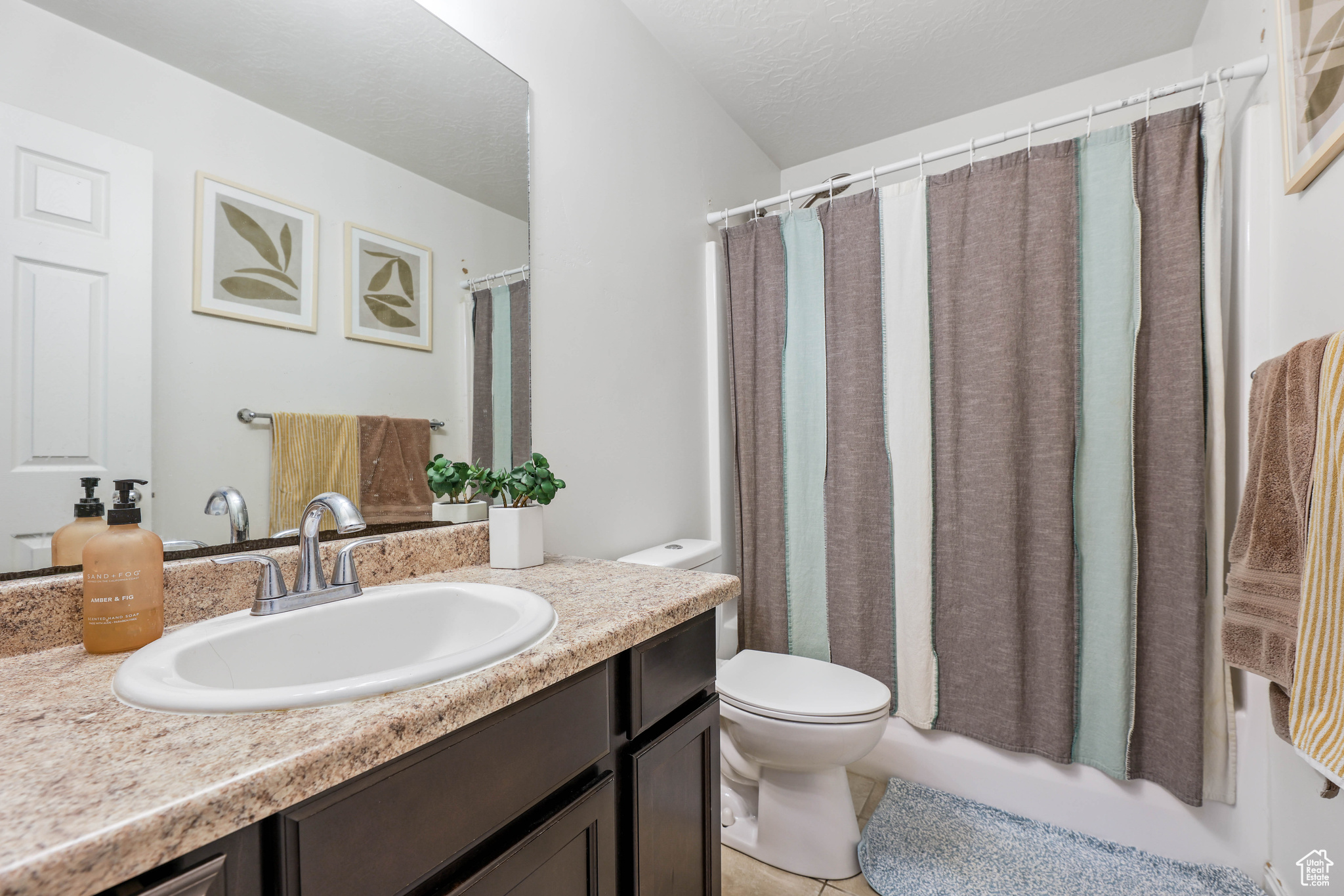 Full bathroom featuring shower / bath combo, vanity, a textured ceiling, tile patterned floors, and toilet