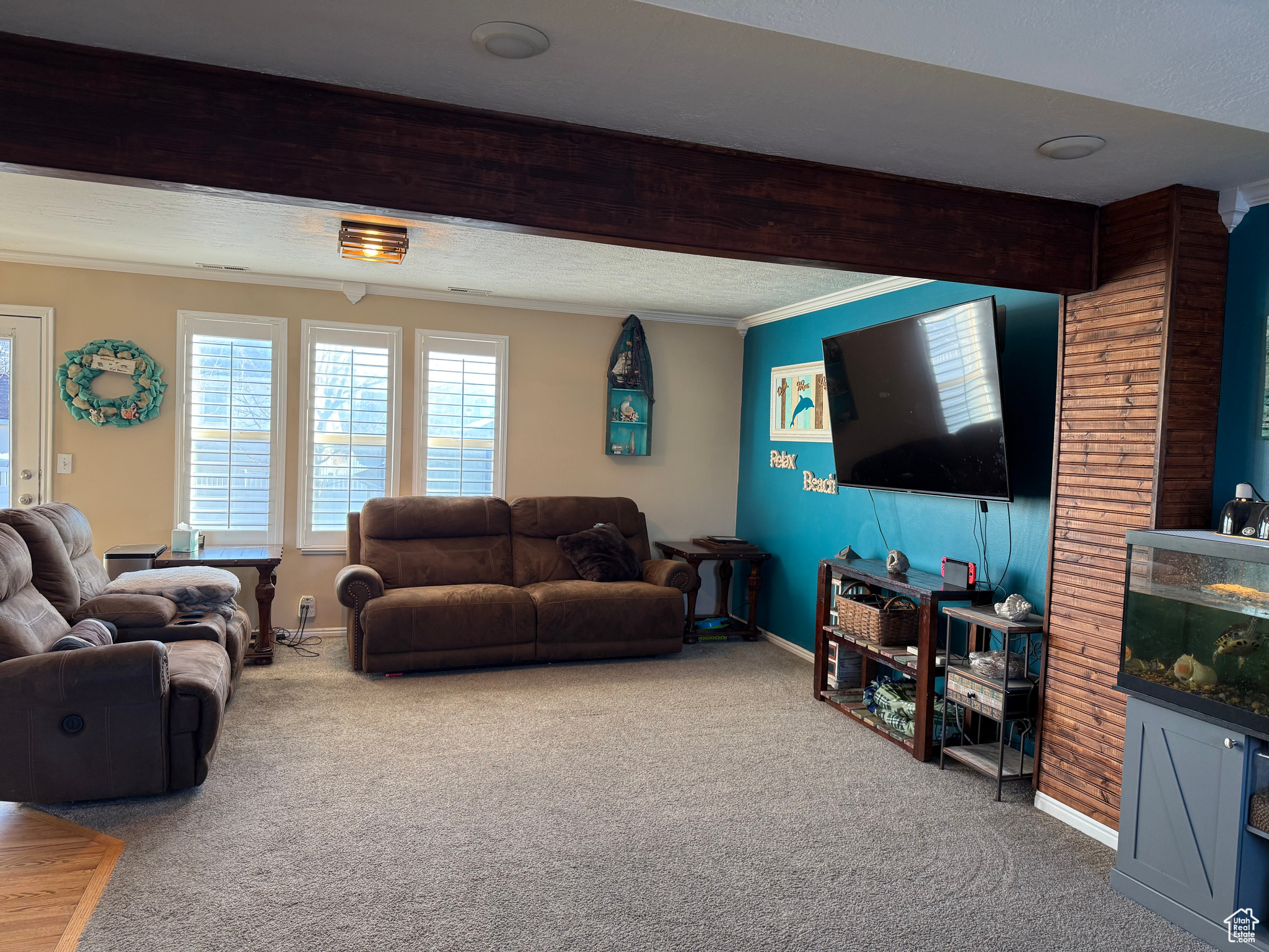 Living room with ornamental molding, carpet flooring, and beam ceiling