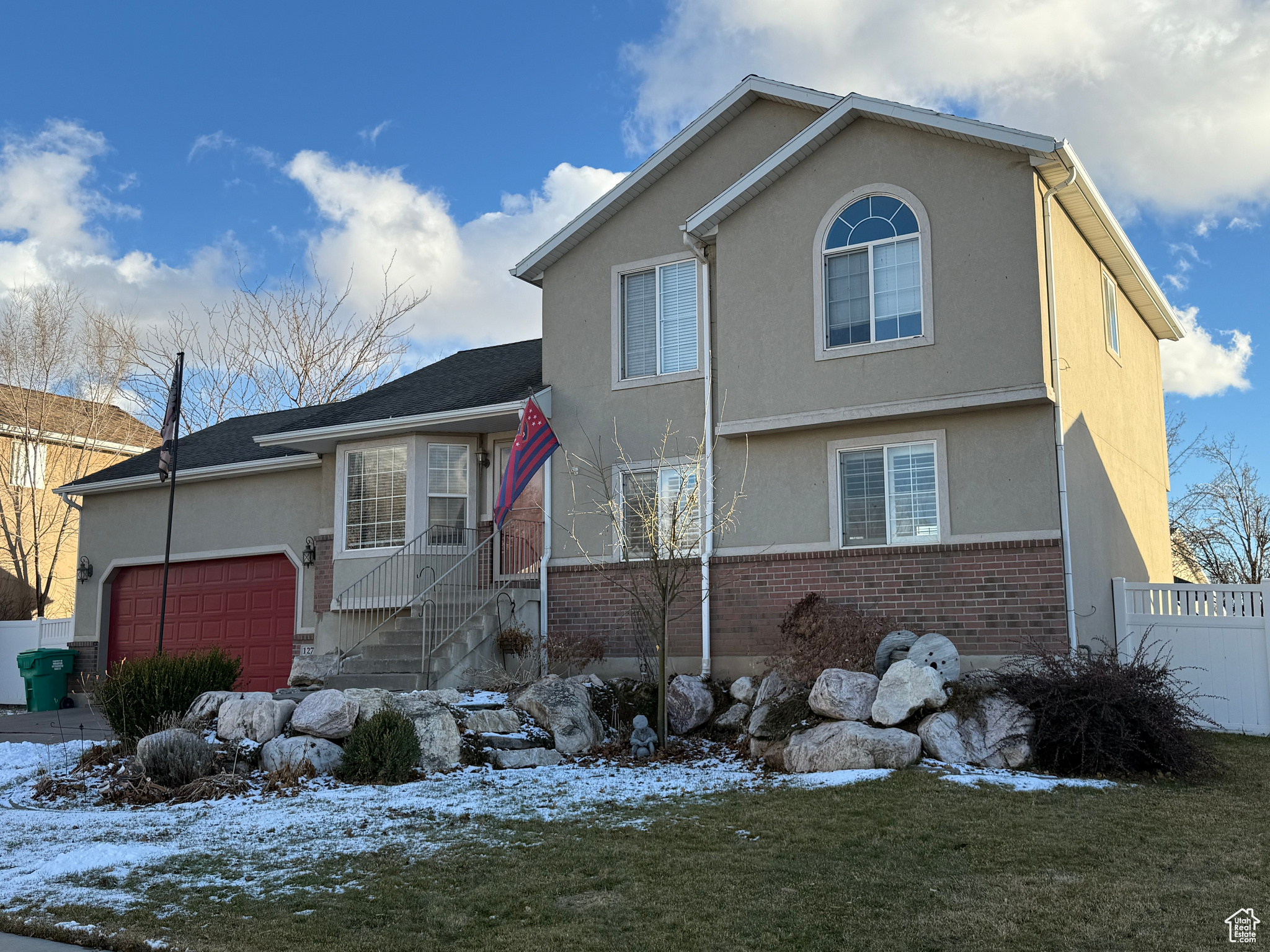 View of front of home featuring a garage, rock and perennial landscaping